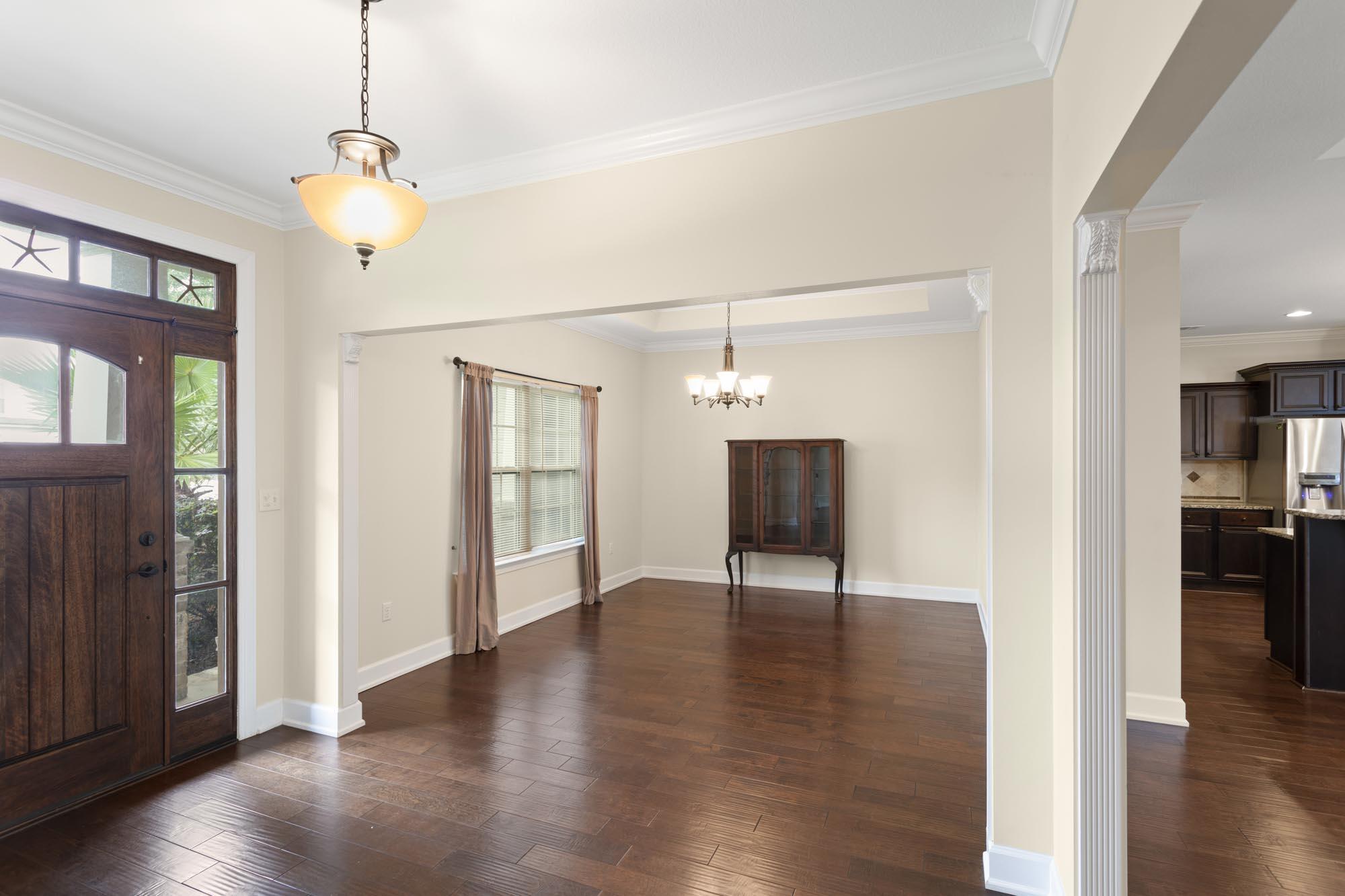 Dining room with dark wood floors, a chandelier, and a view into the kitchen.