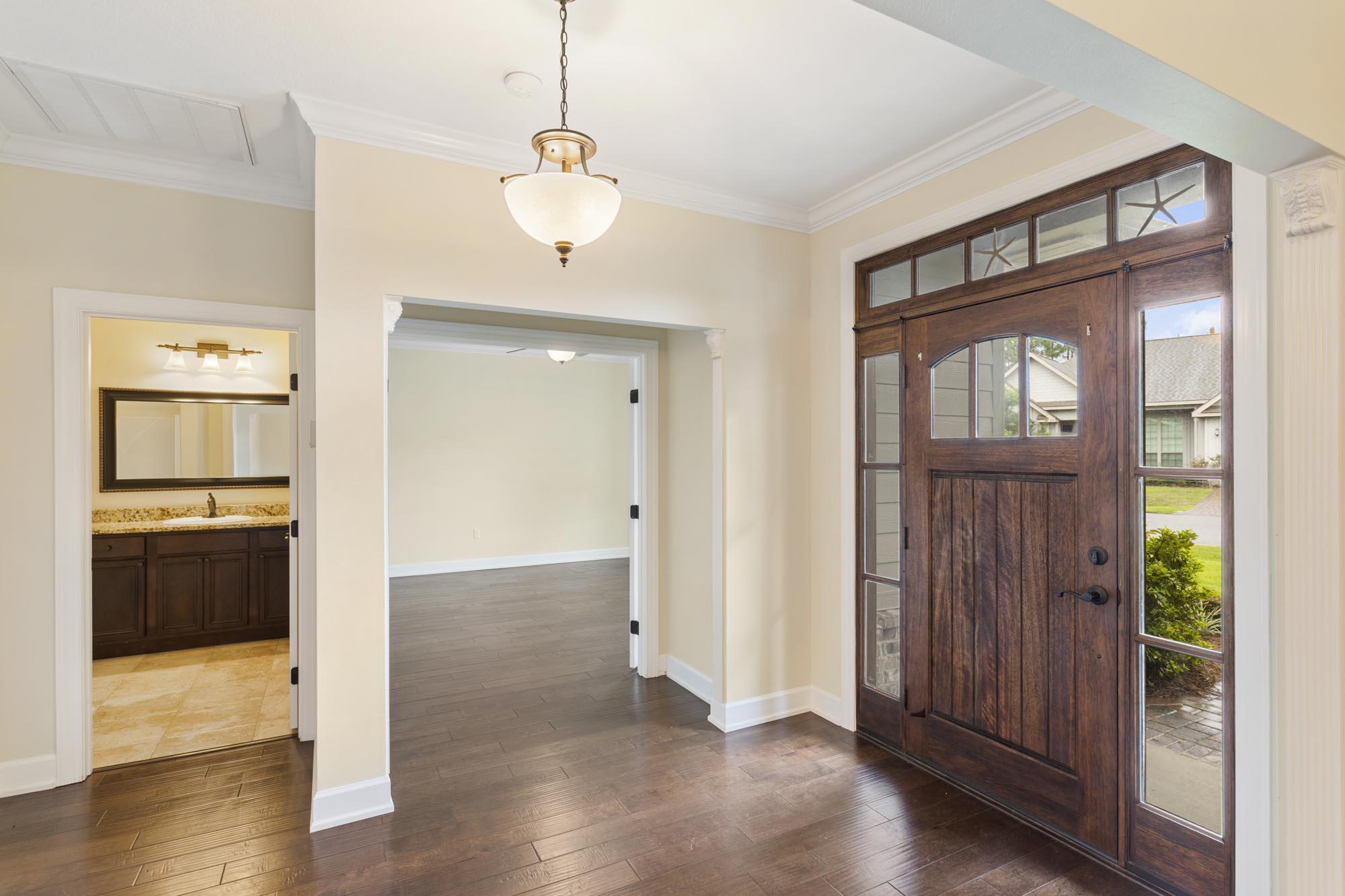 Vacant entryway with a dark wood front door, sidelights, and a view into an empty room.