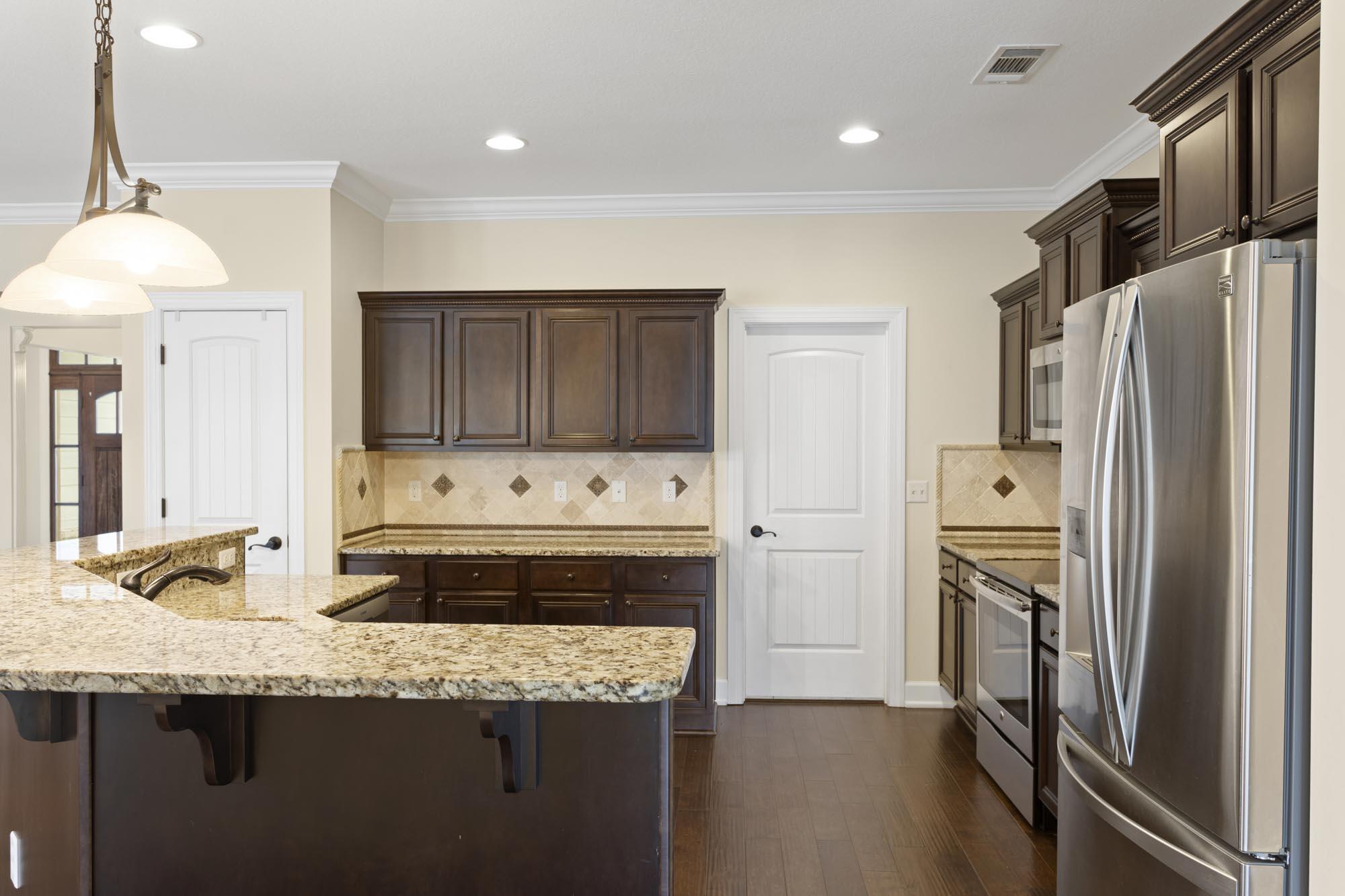 Kitchen with a granite breakfast bar, dark wood cabinetry, and stainless steel appliances.