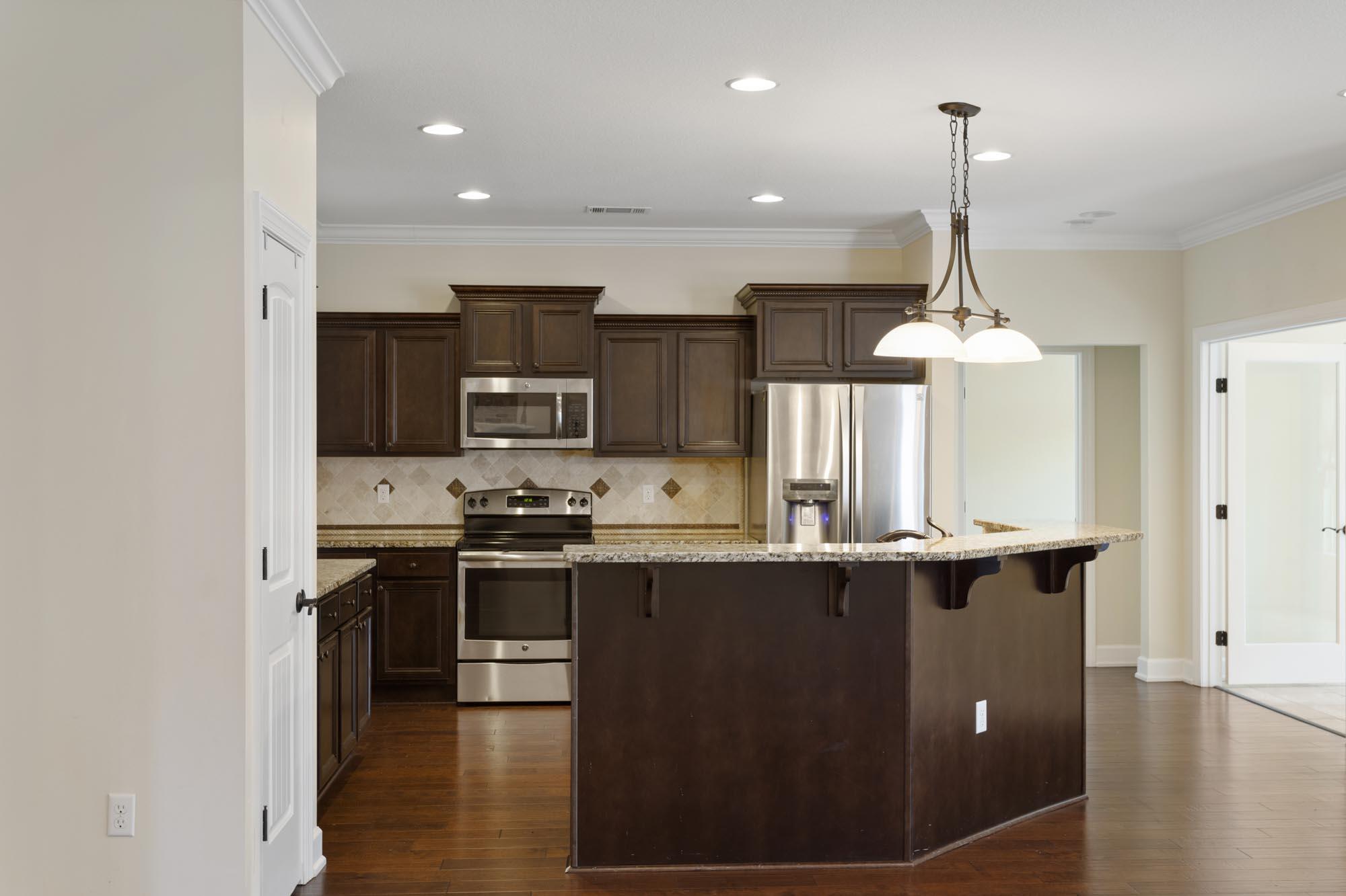Kitchen with dark wood cabinets, stainless steel appliances, and a large granite island.