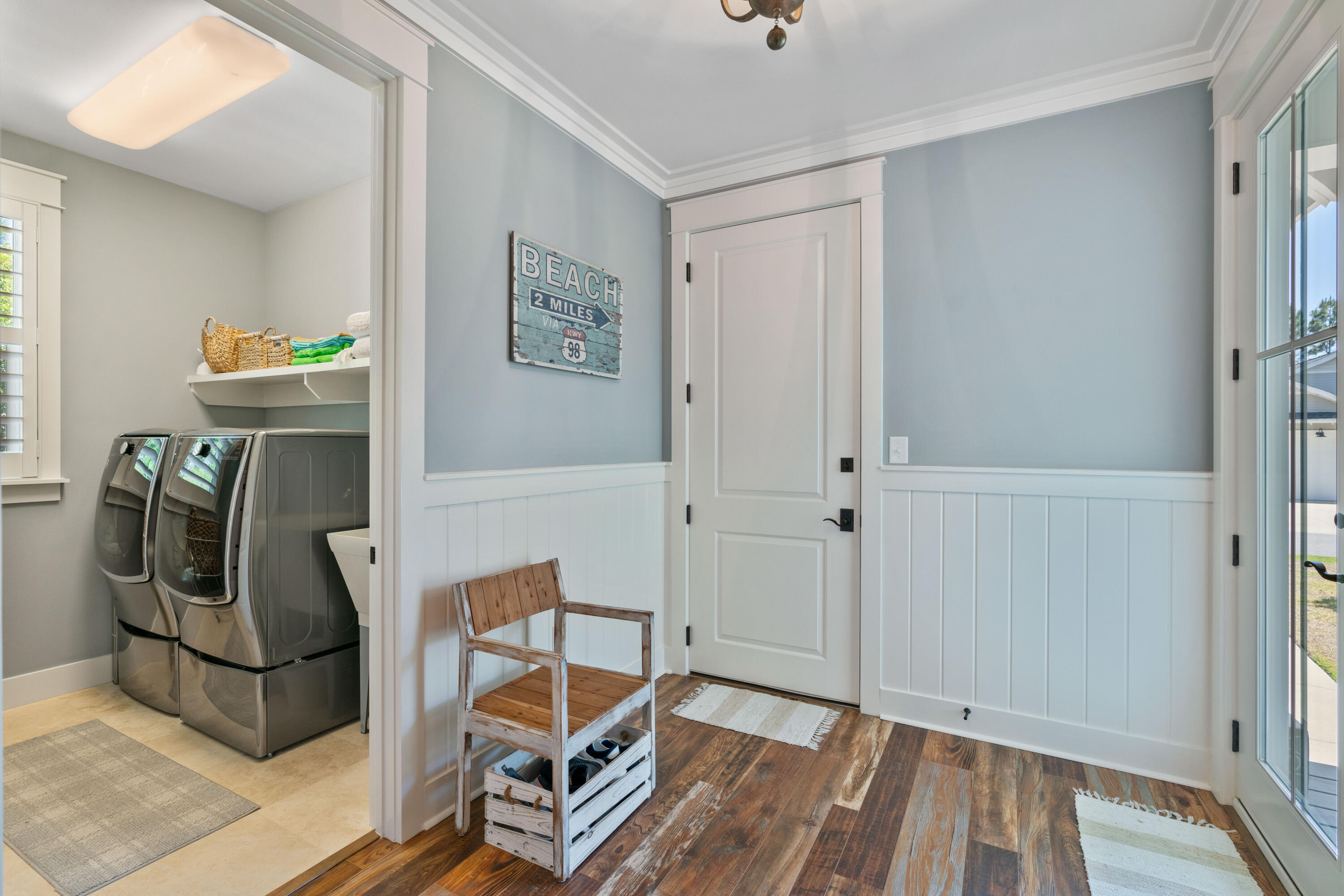 Entryway with a rustic bench and beach sign beside an adjoining laundry area with a washer and dryer.