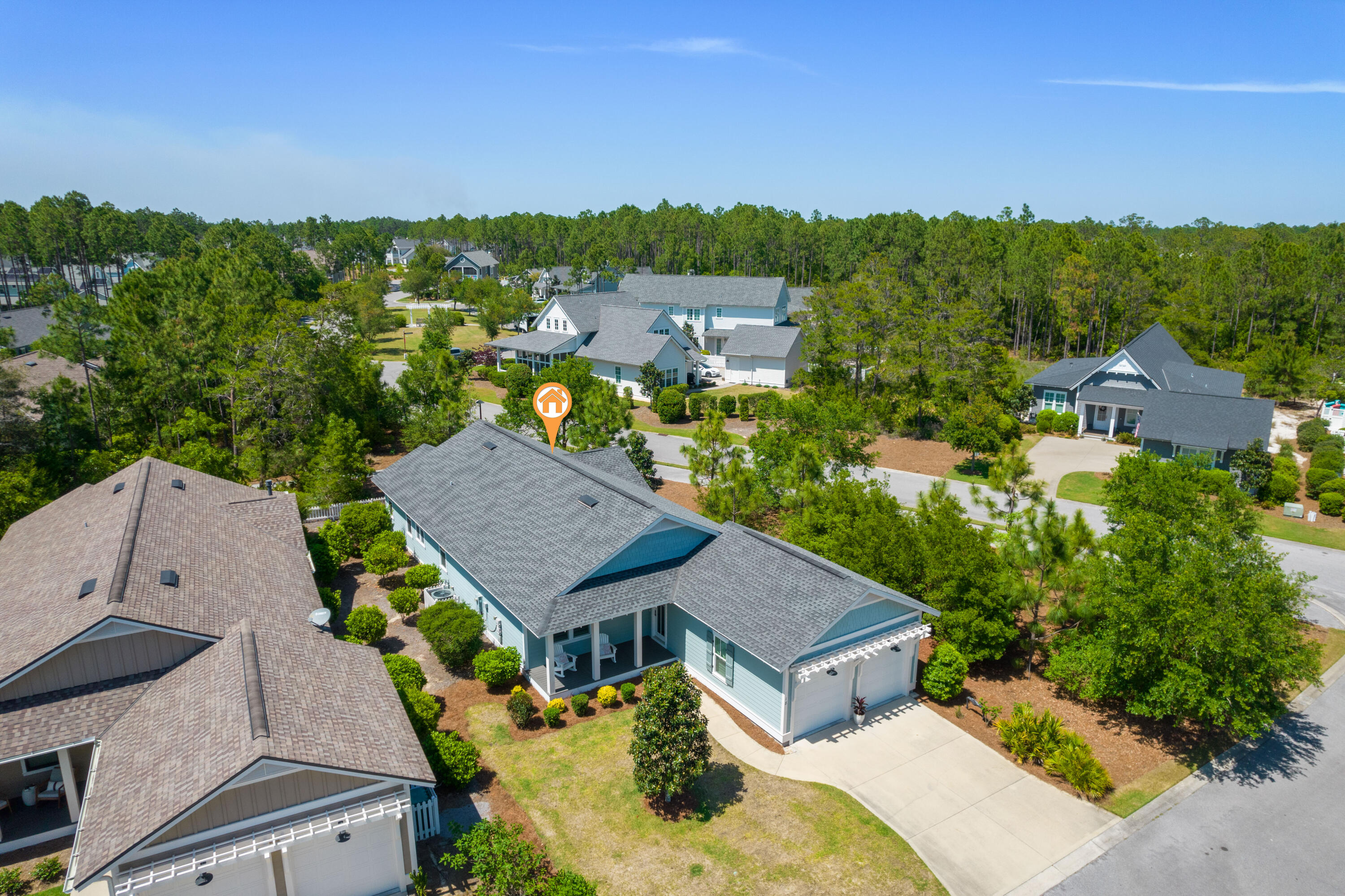 Aerial view of a light blue house with a gray roof, covered porch, and orange property marker.