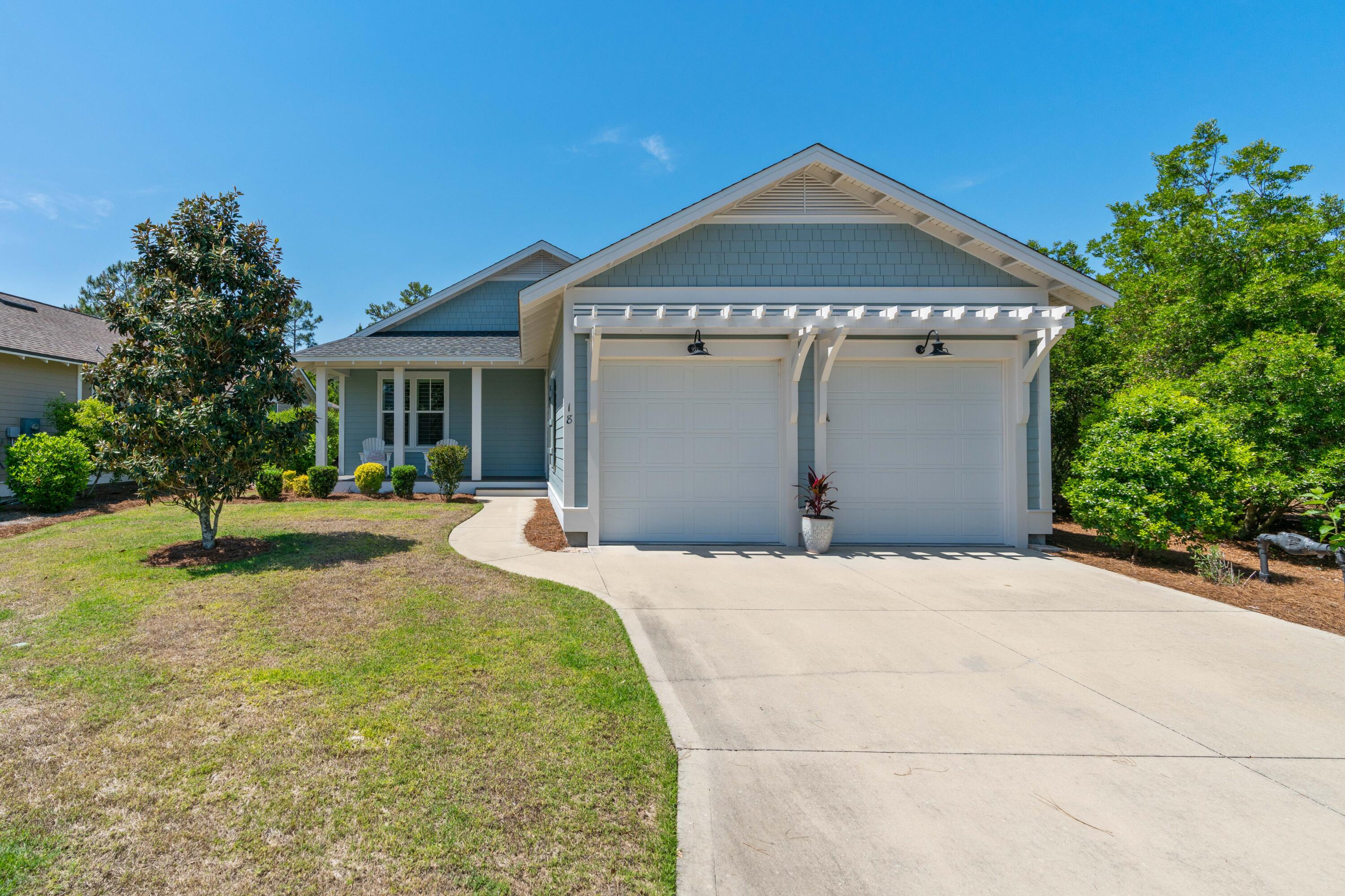 Gray-shingled home with white trim, double garage, and curved driveway.