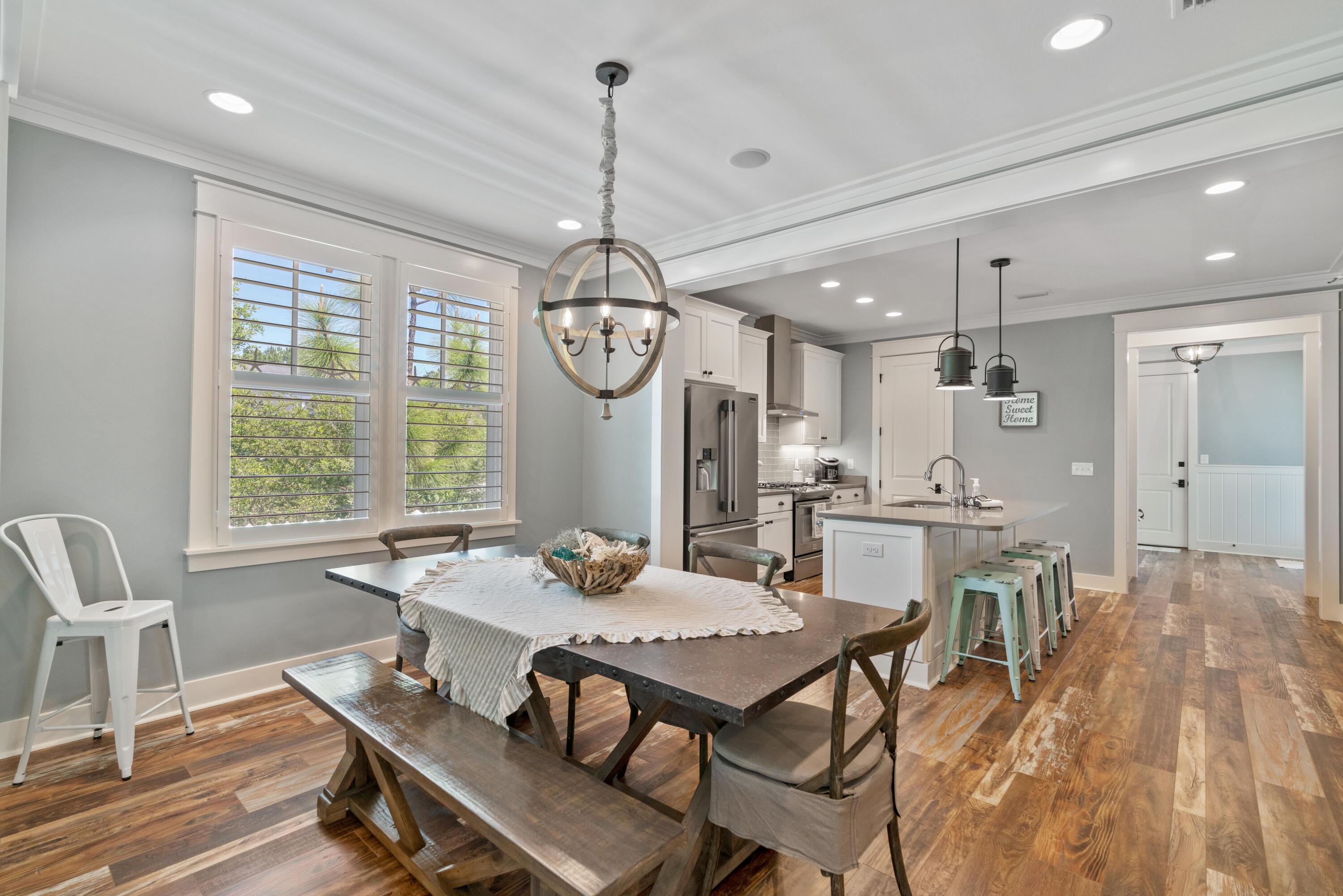 Open-plan kitchen and dining area with a farmhouse table, central island, and shuttered windows.