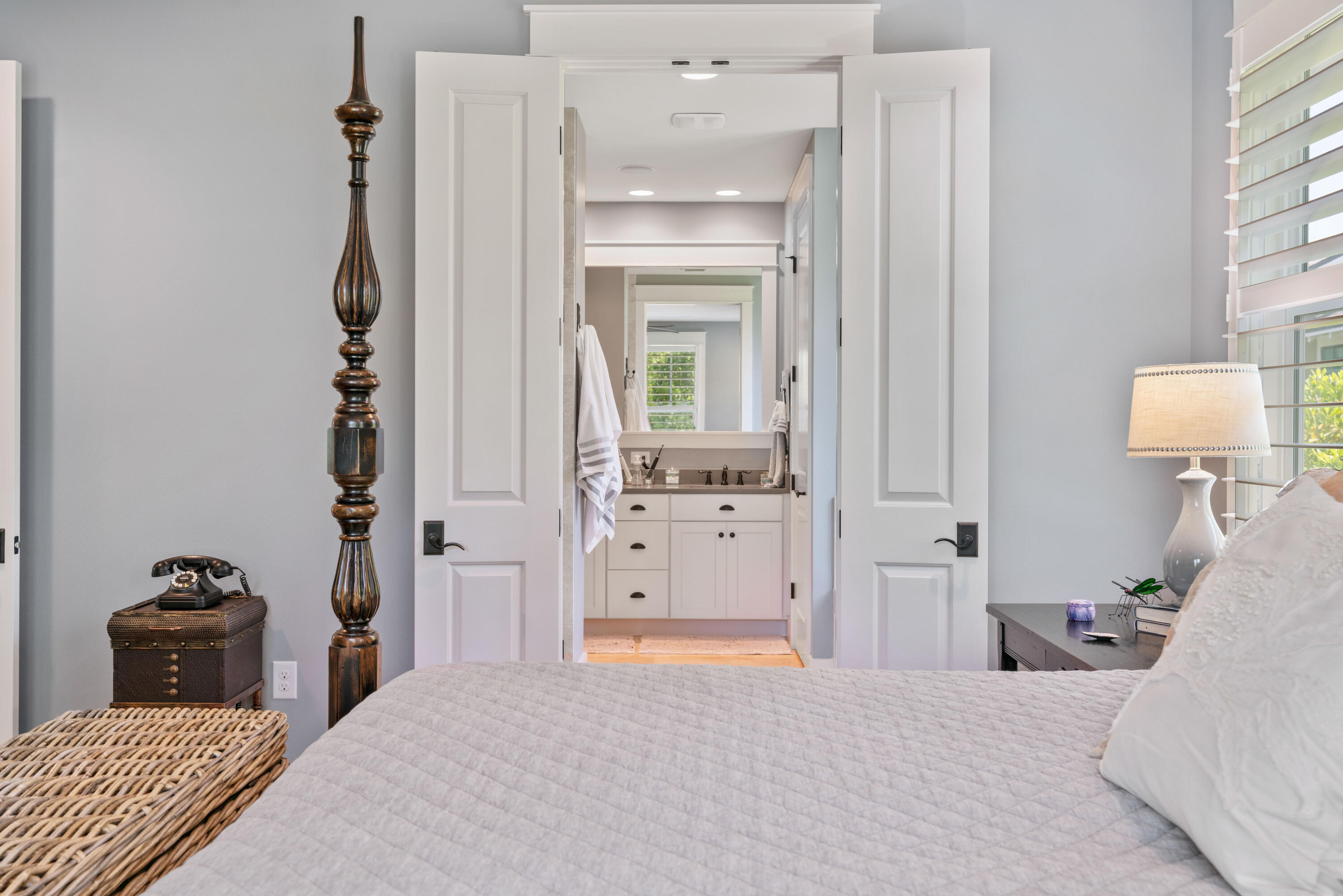 Bedroom with white bedding and open double doors to an ensuite bathroom.