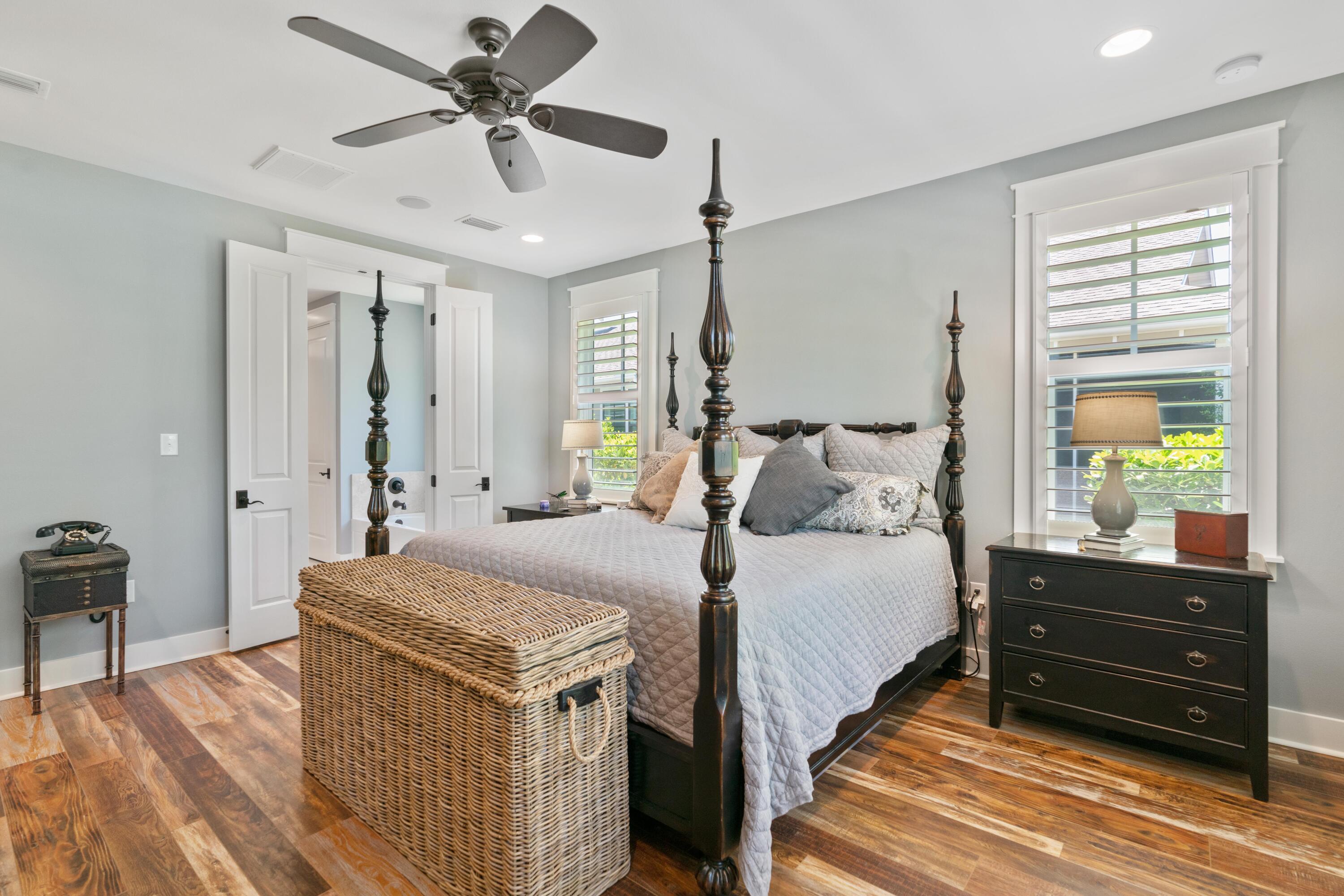 Bedroom with a dark four-poster bed, shuttered windows, and a woven trunk at its foot.