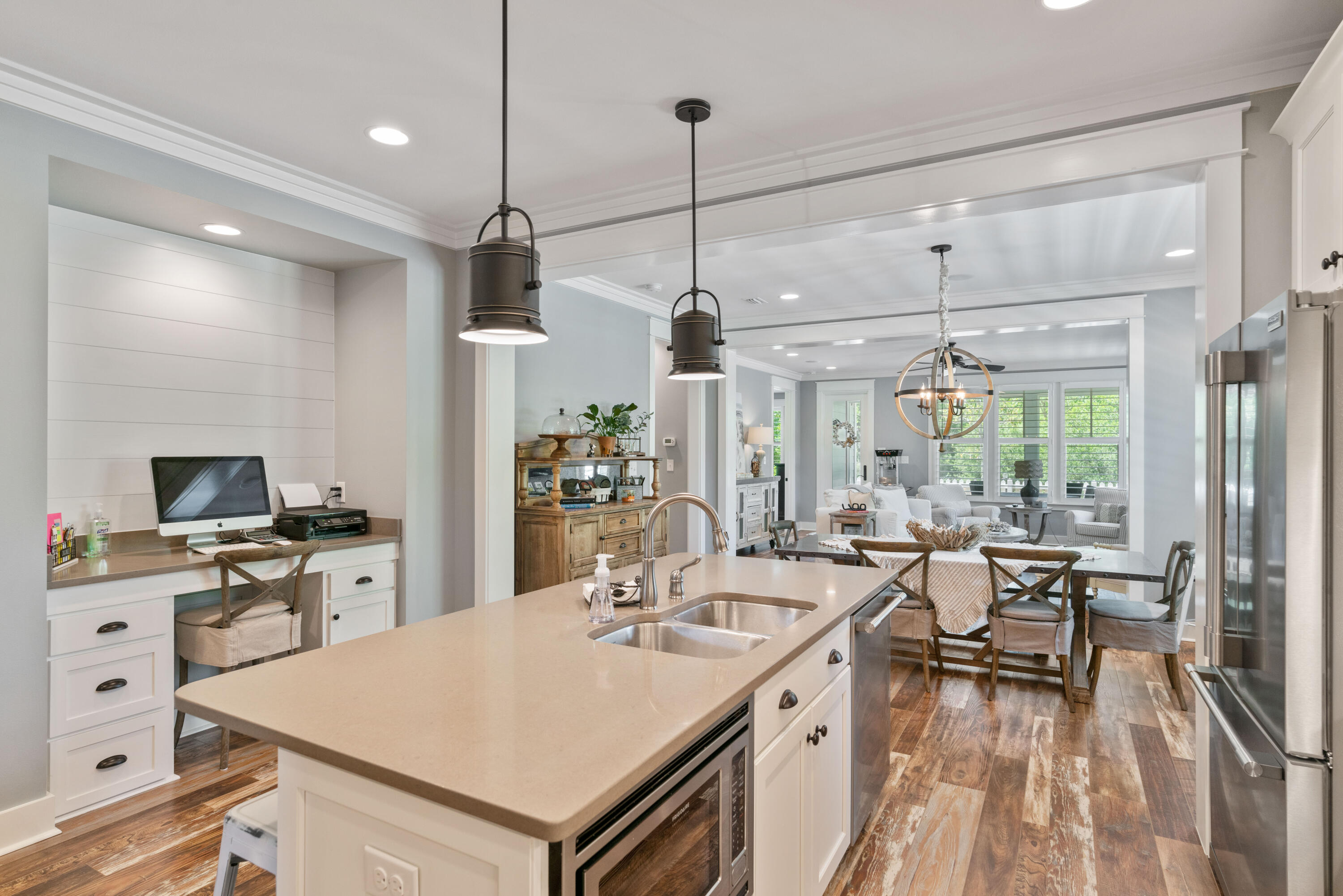 Open-plan kitchen with a large island and pendant lights, opening to a dining and living area.