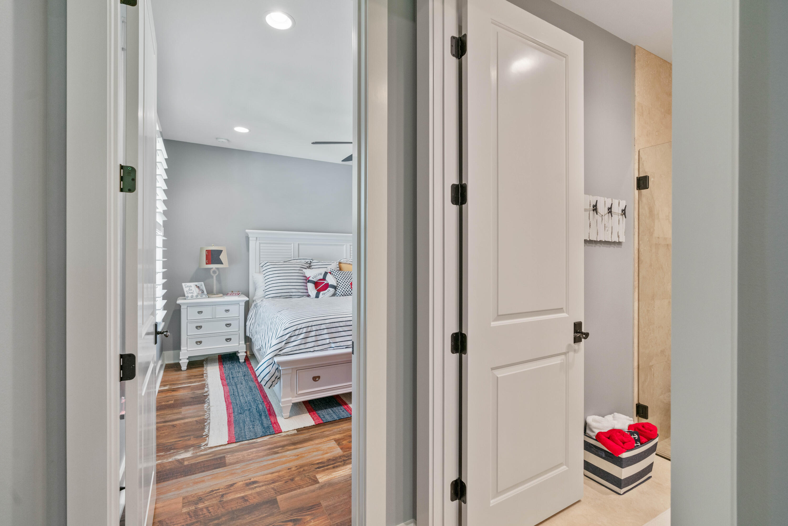 Bedroom with nautical striped bedding, a colorful rug, and an open doorway to a tiled space.