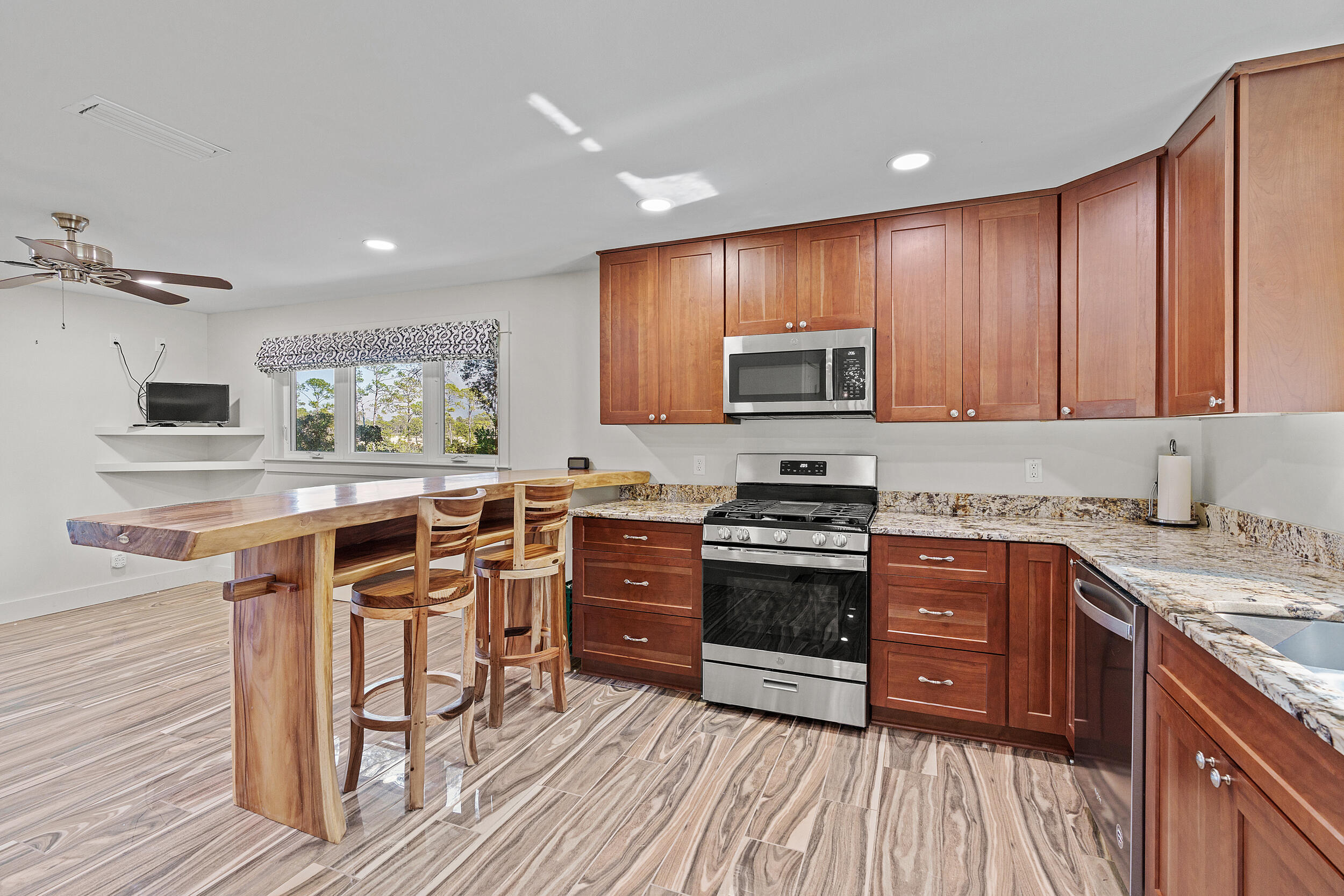 Kitchen with wood cabinets, granite counters, and a butcher-block breakfast bar with stools.