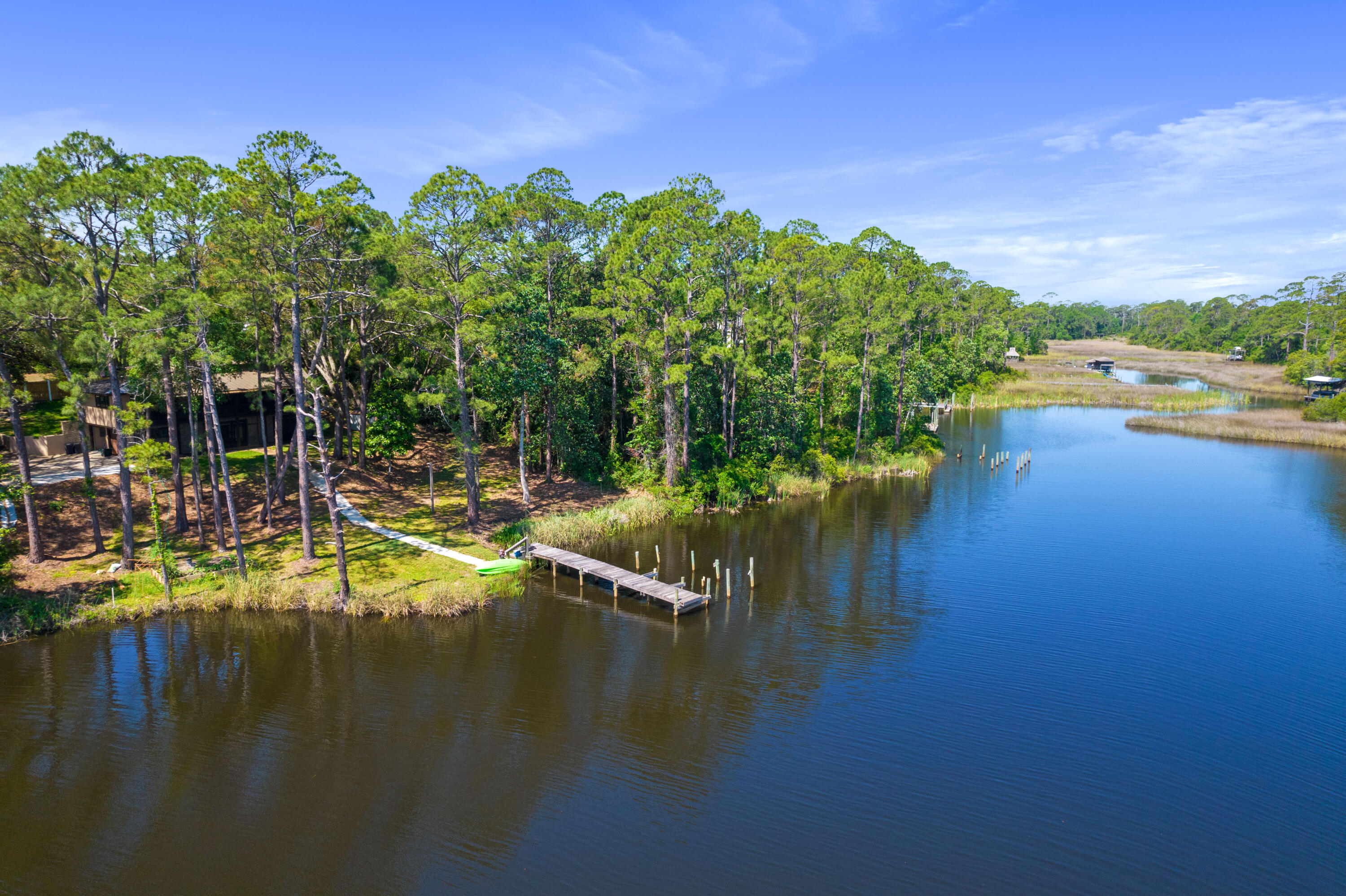 Aerial view of a wooded waterfront home with a private dock and kayak on the inlet.
