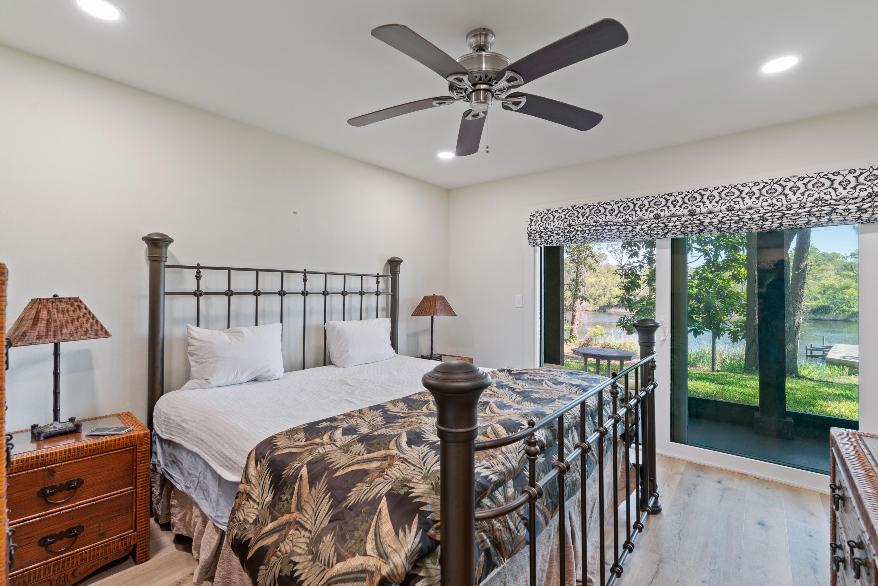 Bedroom with a dark four-poster bed and sliding doors overlooking the water.