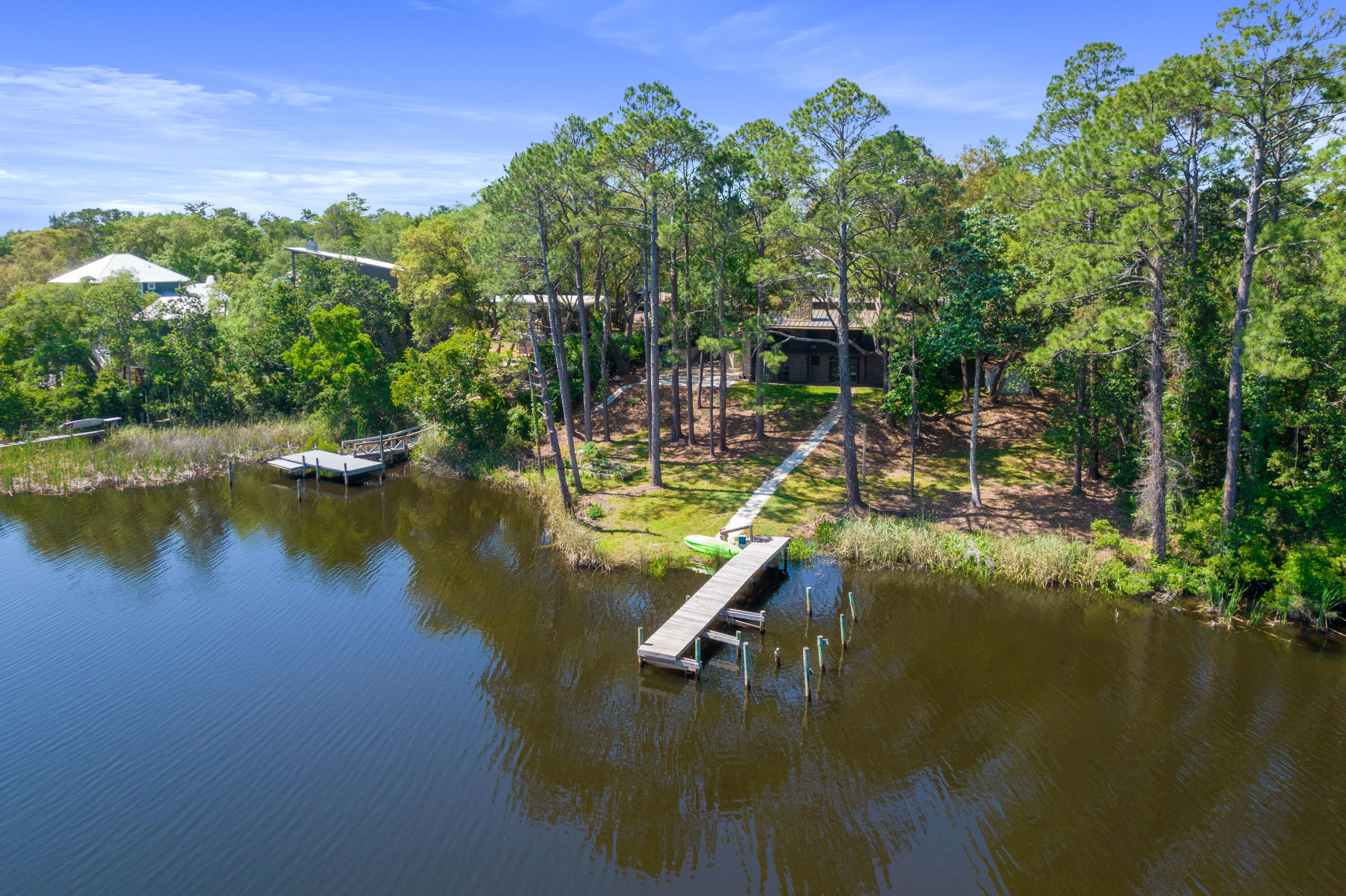 Aerial view of a wooded waterfront home with two docks extending into the water.