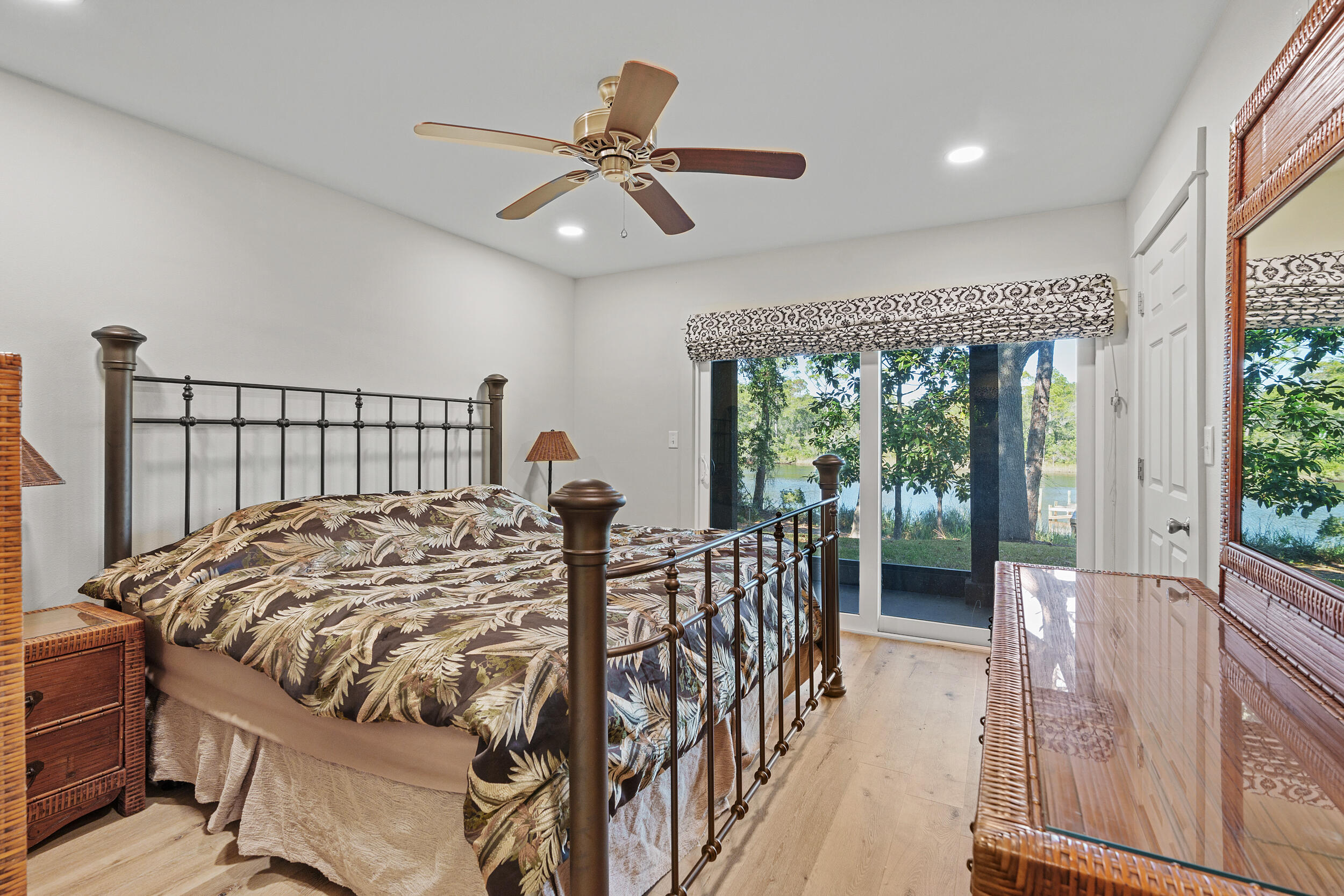 Bedroom with a four-poster bed and sliding glass doors overlooking water and trees.