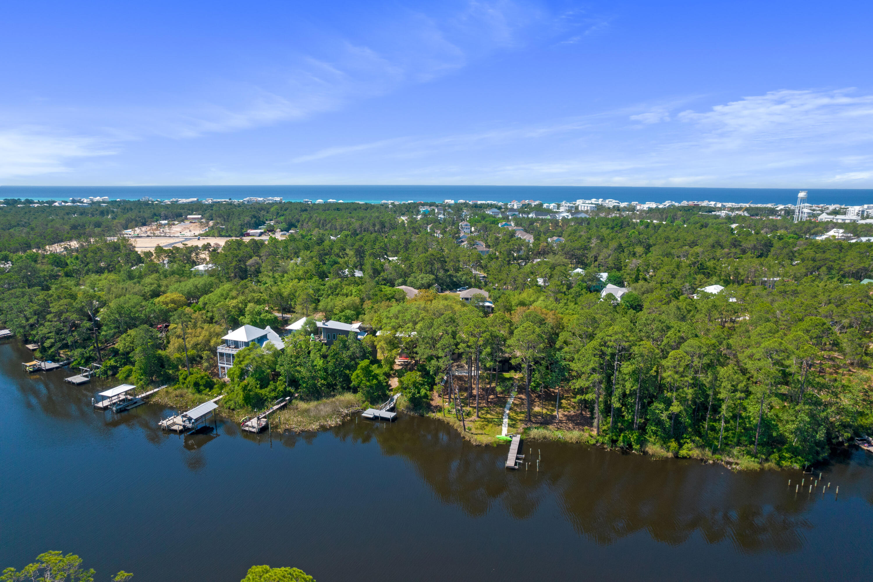 Aerial view of wooded homes along an inlet, with docks and the Gulf coast on the horizon.