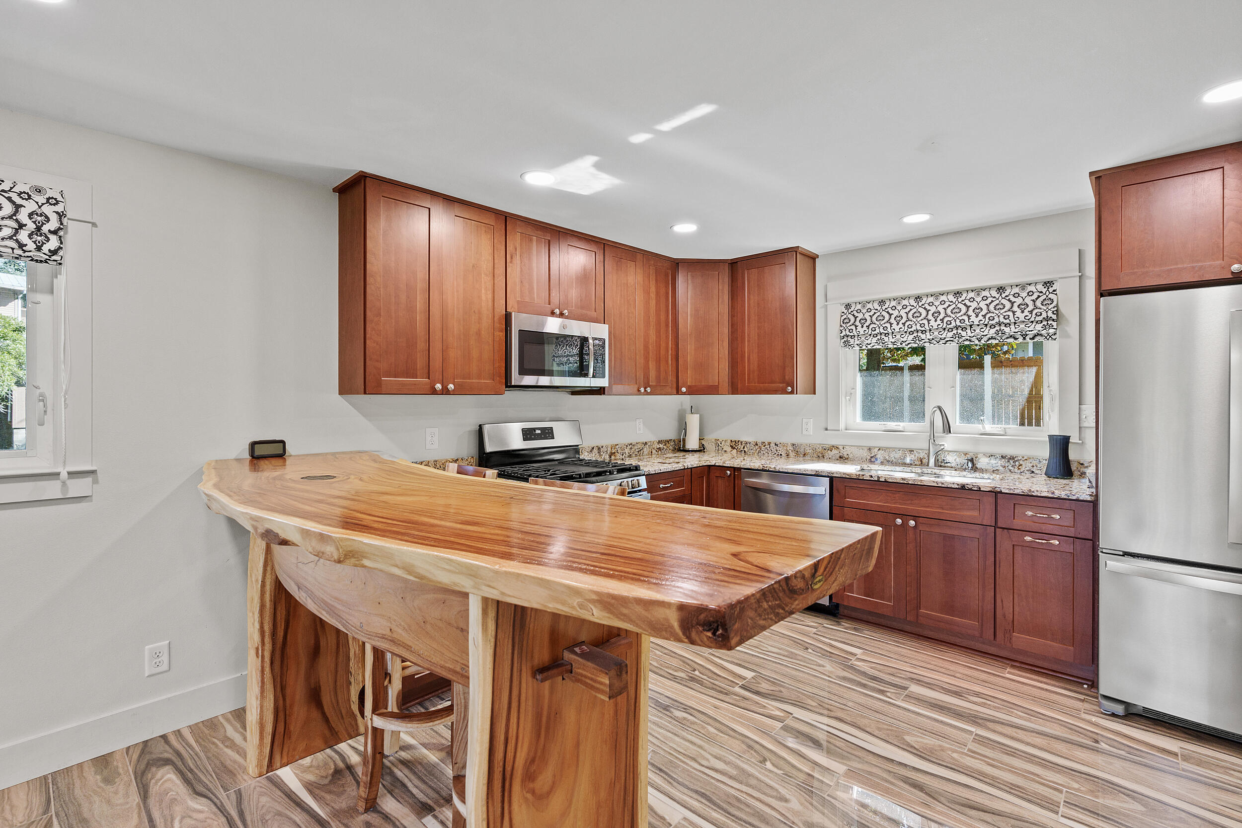 Kitchen with rich wood cabinetry, stainless steel appliances, and a large live-edge island.