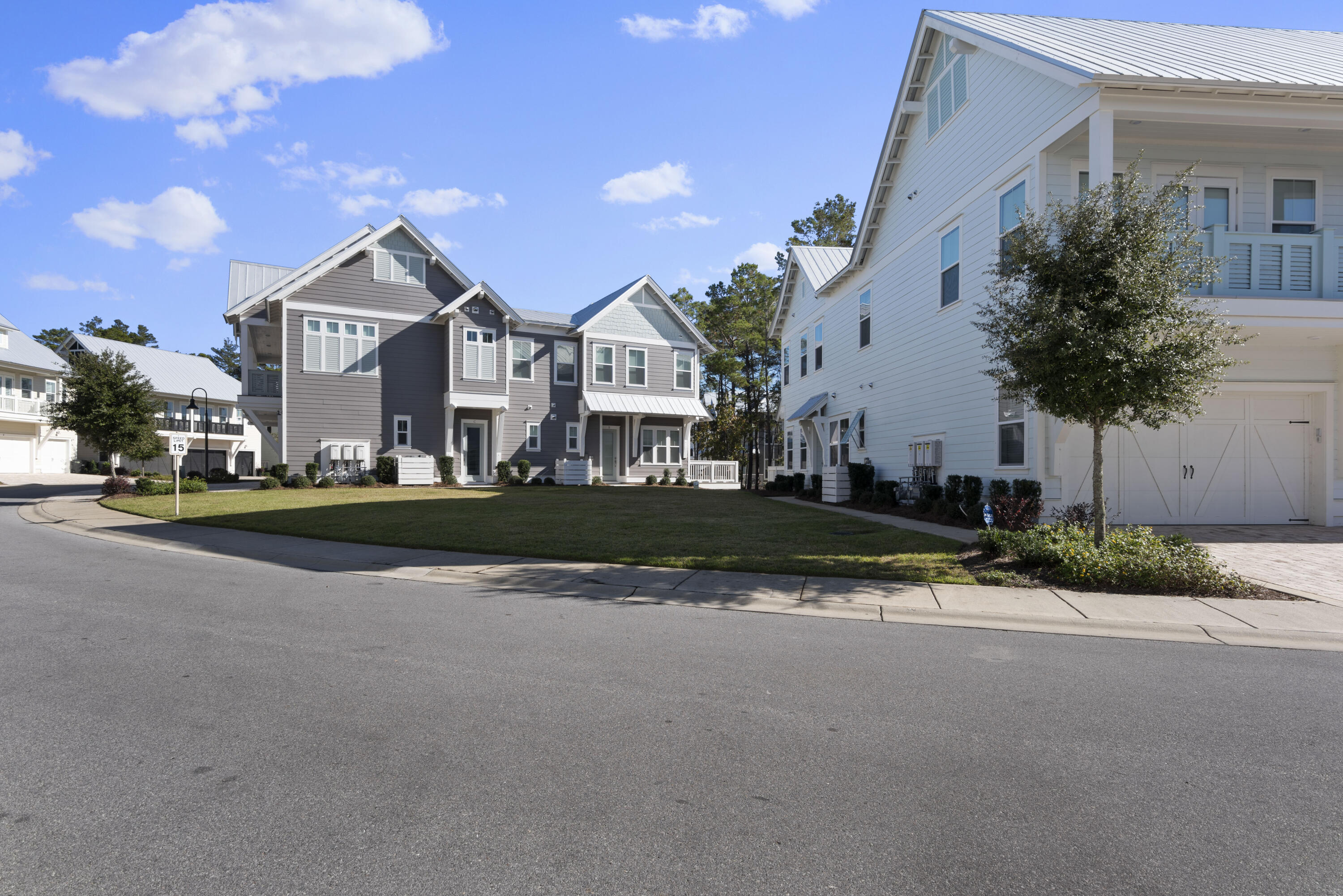 Gray multi-story home with white trim and gabled roofs beside a small lawn.