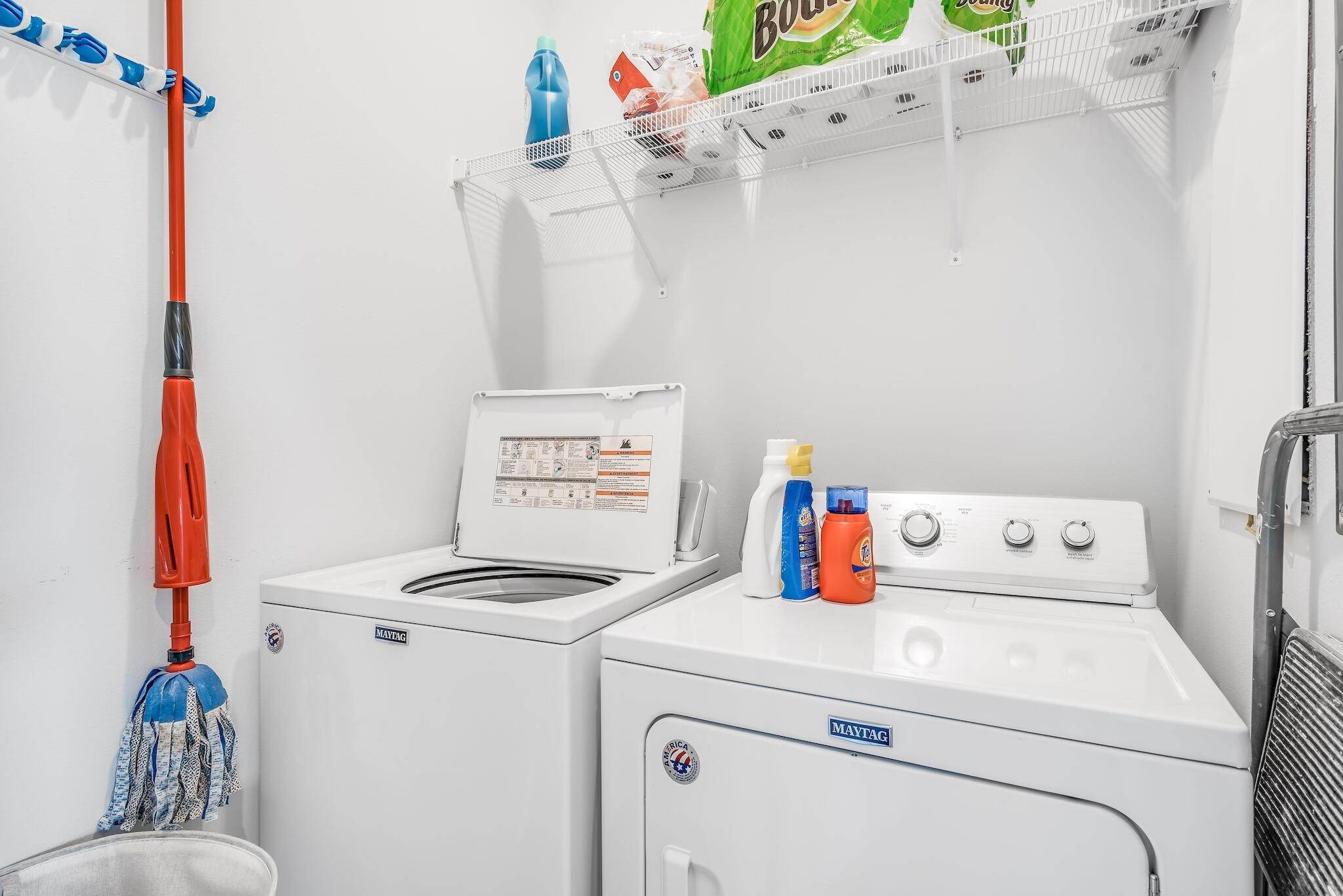 Laundry room with matching Maytag washer and dryer, detergent bottles, and a mop.