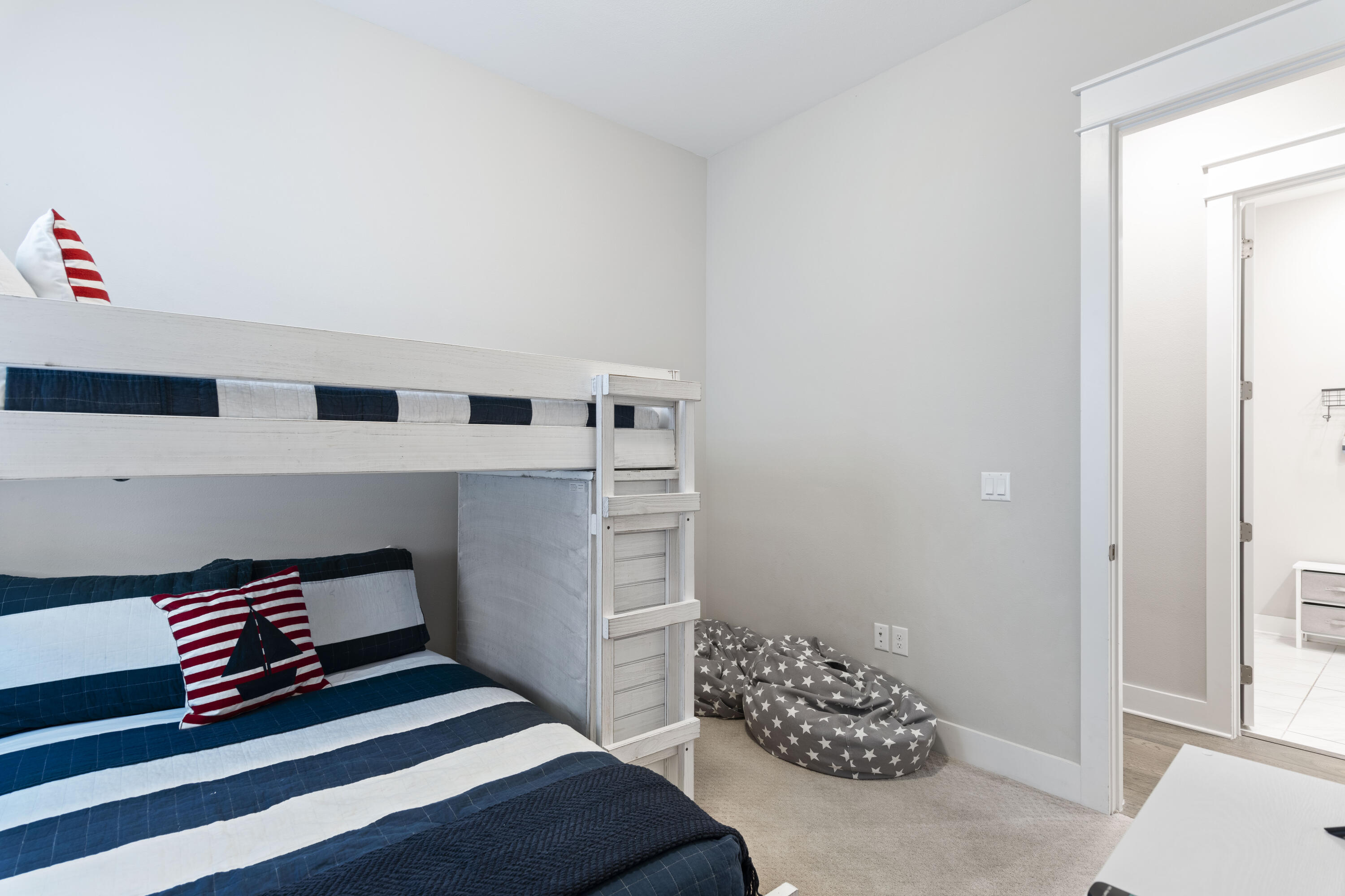 Bedroom with a white bunk bed, striped navy bedding, and a gray star-patterned beanbag.