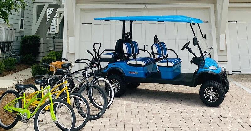 Blue golf cart and several bicycles parked in front of a white garage.