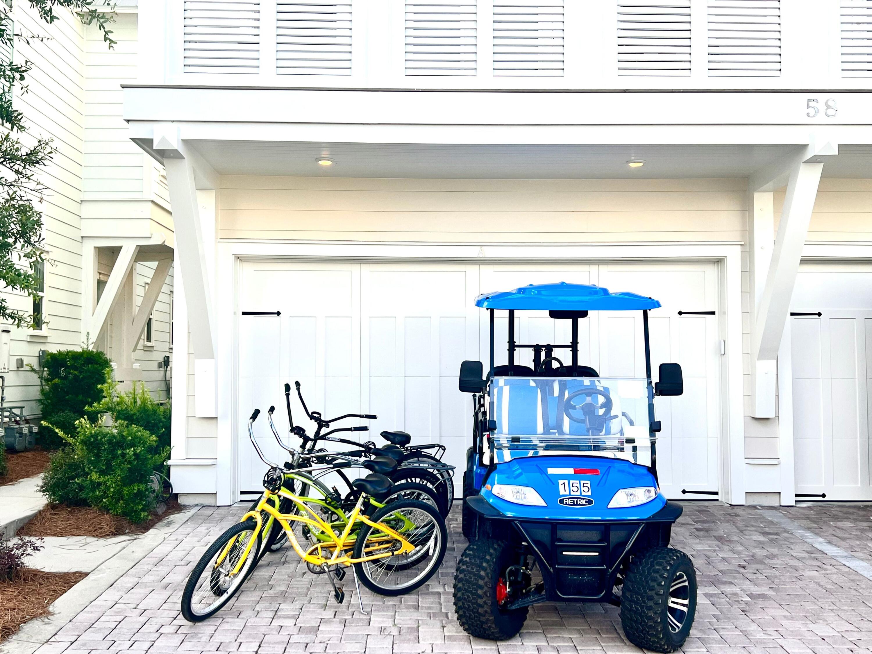 Garage and paved driveway with a blue golf cart and several bicycles parked outside.