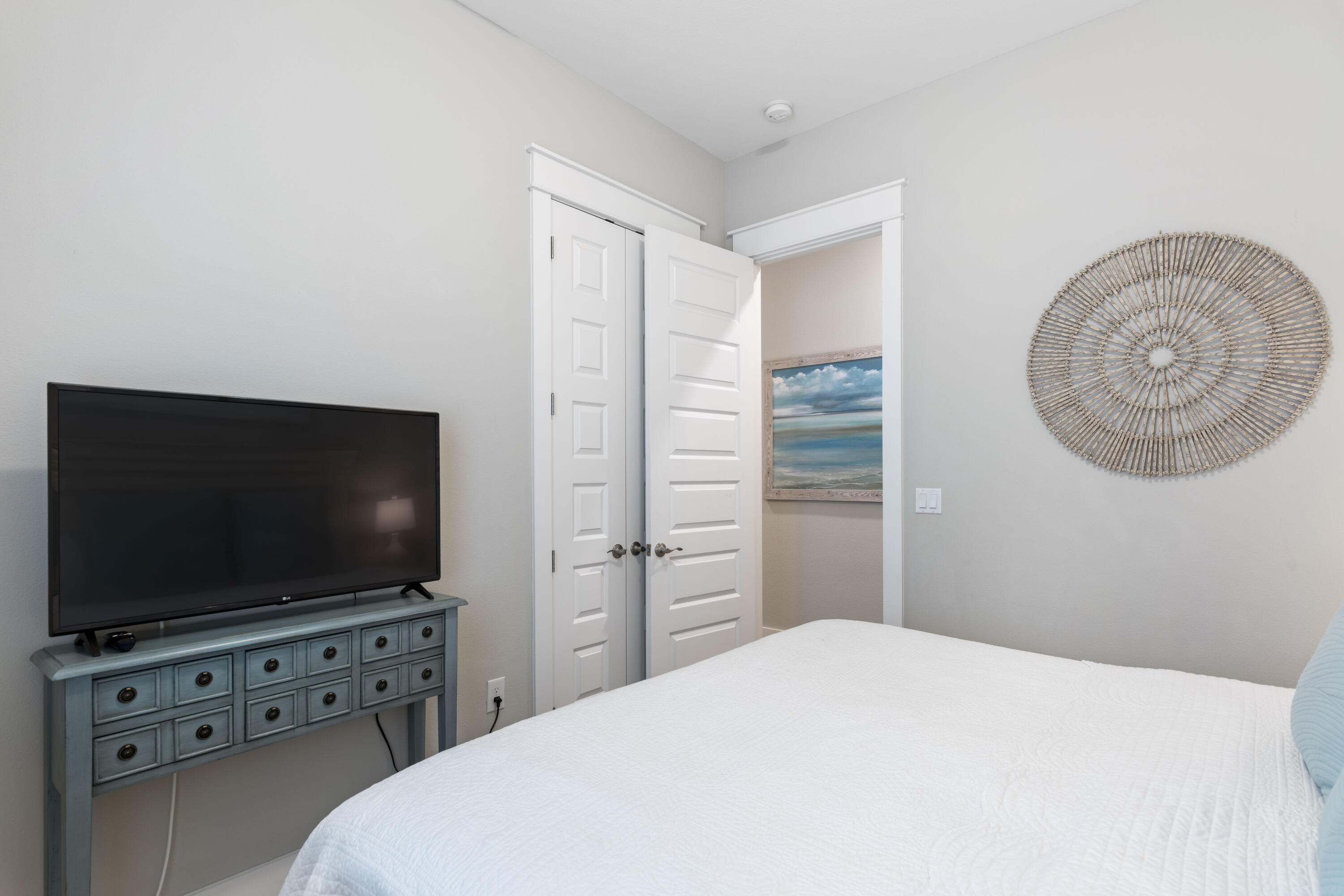 Bedroom with a white bed, television on a blue console, and coastal decor.