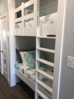 Built-in bunk beds with teal patterned bedding and white ladder shelves.