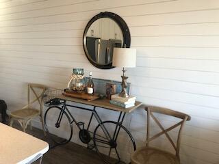 Dining area with a console table, round mirror, and chairs against white plank walls.