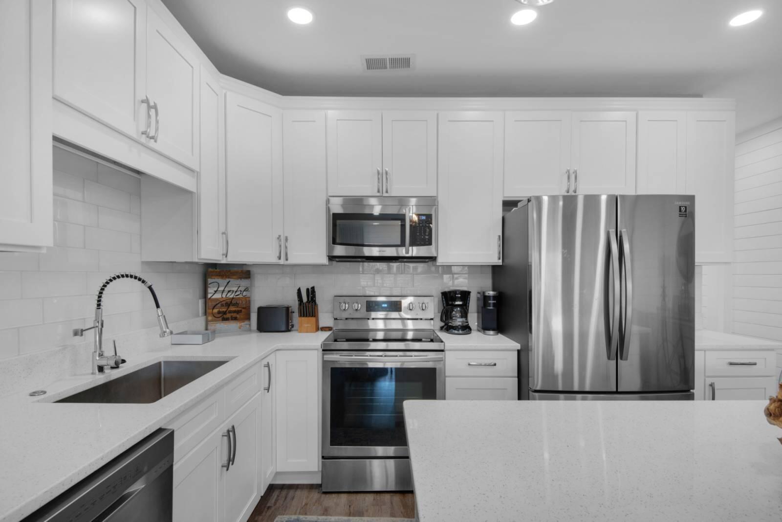 Kitchen with white cabinetry, stainless steel appliances, and a large peninsula.