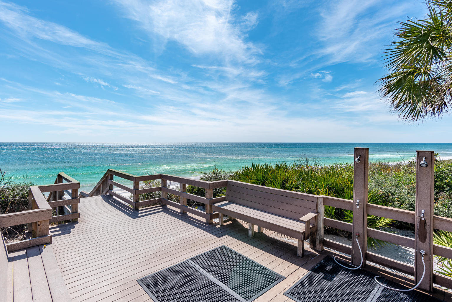 Beach-access deck with outdoor showers and bench seating overlooking the ocean.