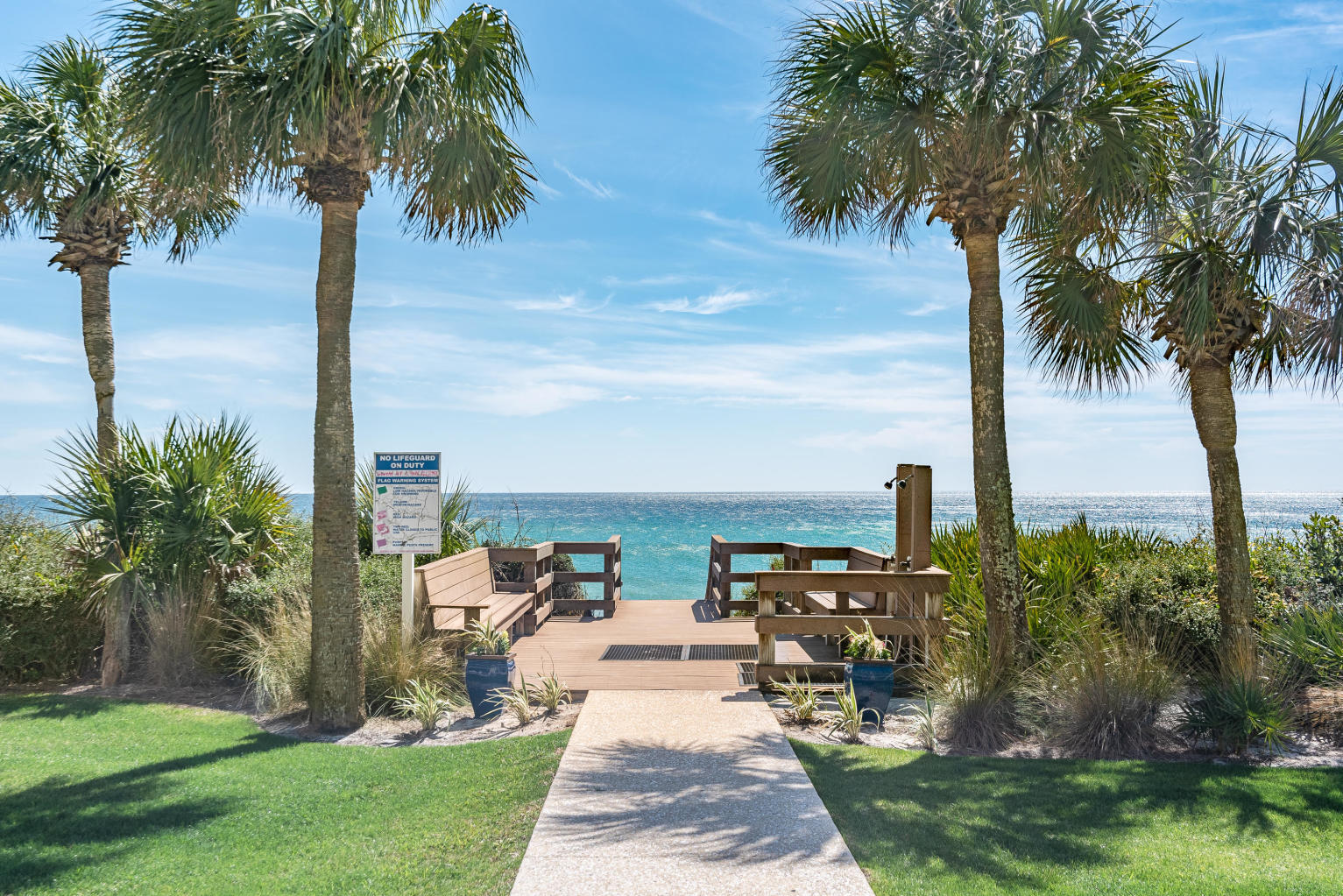 Beach access deck and outdoor shower framed by palm trees, overlooking the ocean.