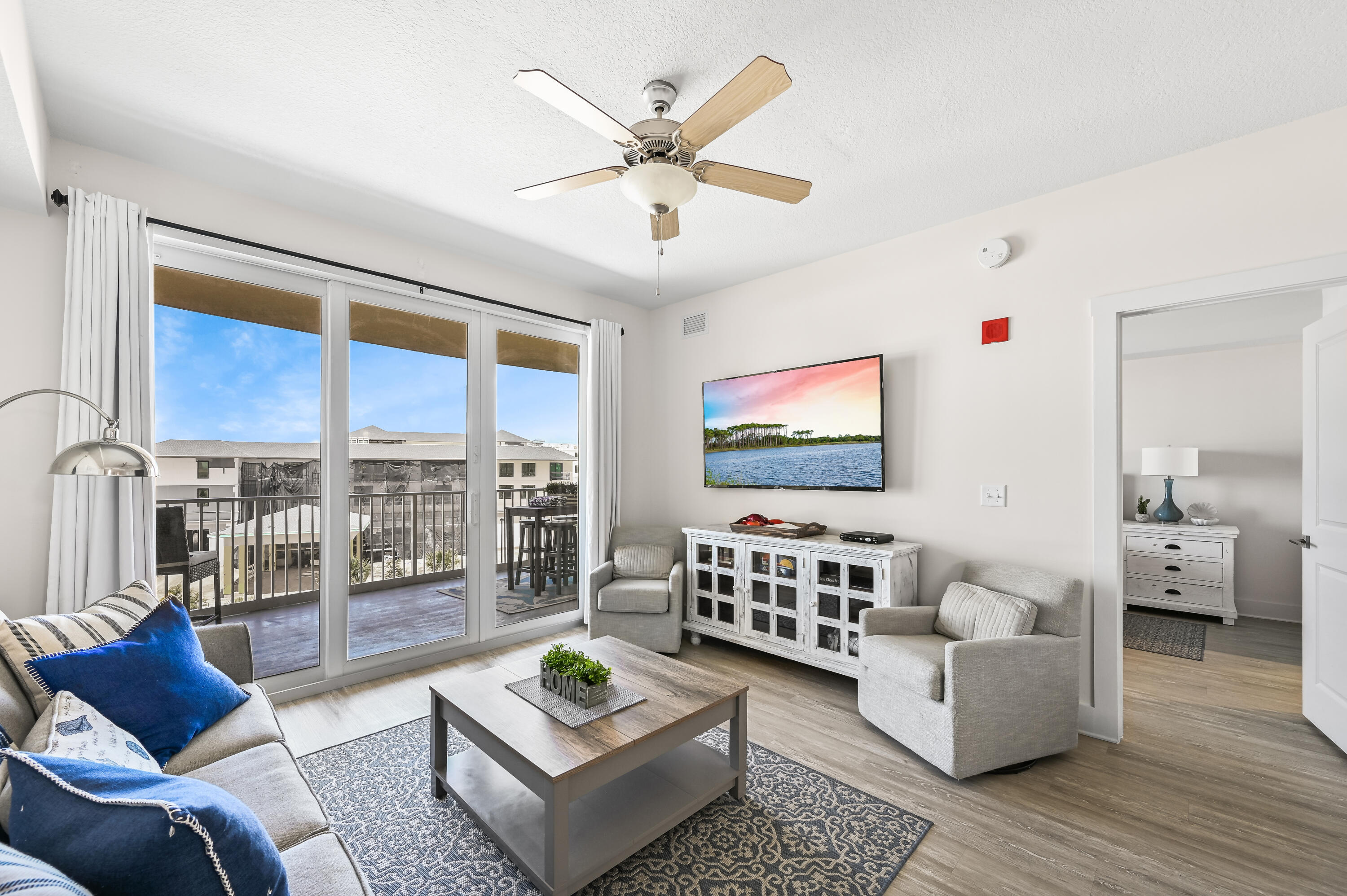 Living room with gray seating, a patterned rug, and sliding doors opening to a balcony.