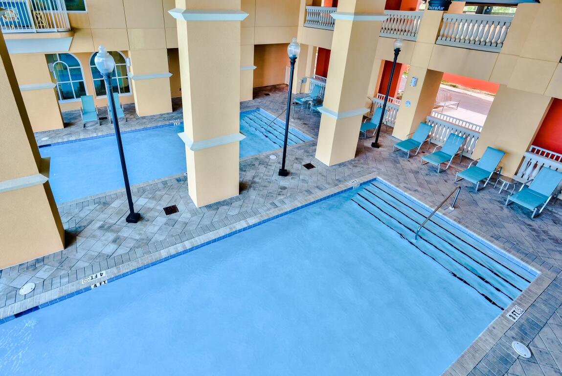 Covered courtyard swimming pool with submerged steps, tiled deck, and turquoise lounge chairs.