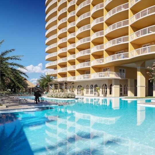 Condominium pool beside a curved yellow high-rise with white balconies and palm trees.