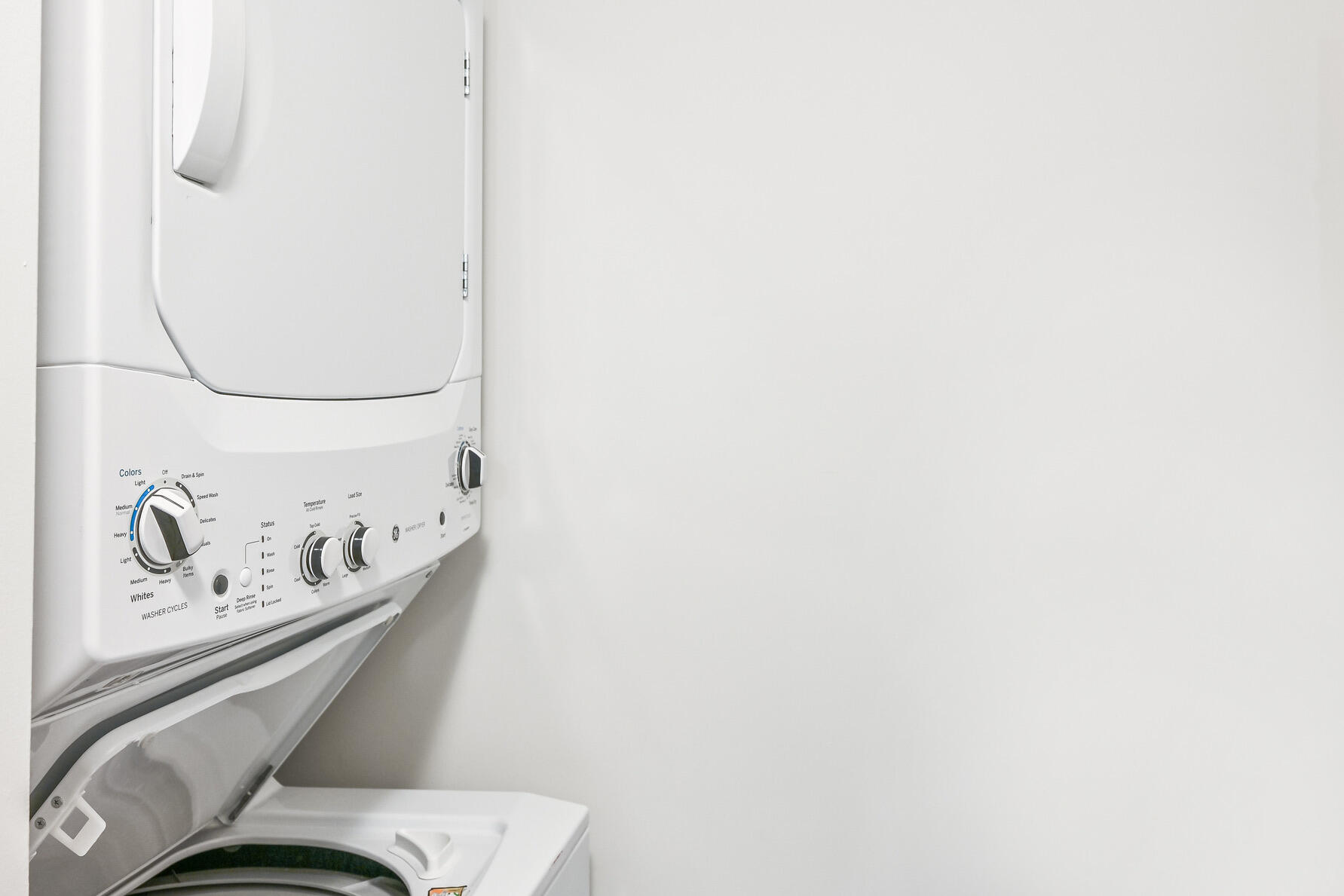 Stacked white washer and dryer with the washer lid open and cycle controls visible.