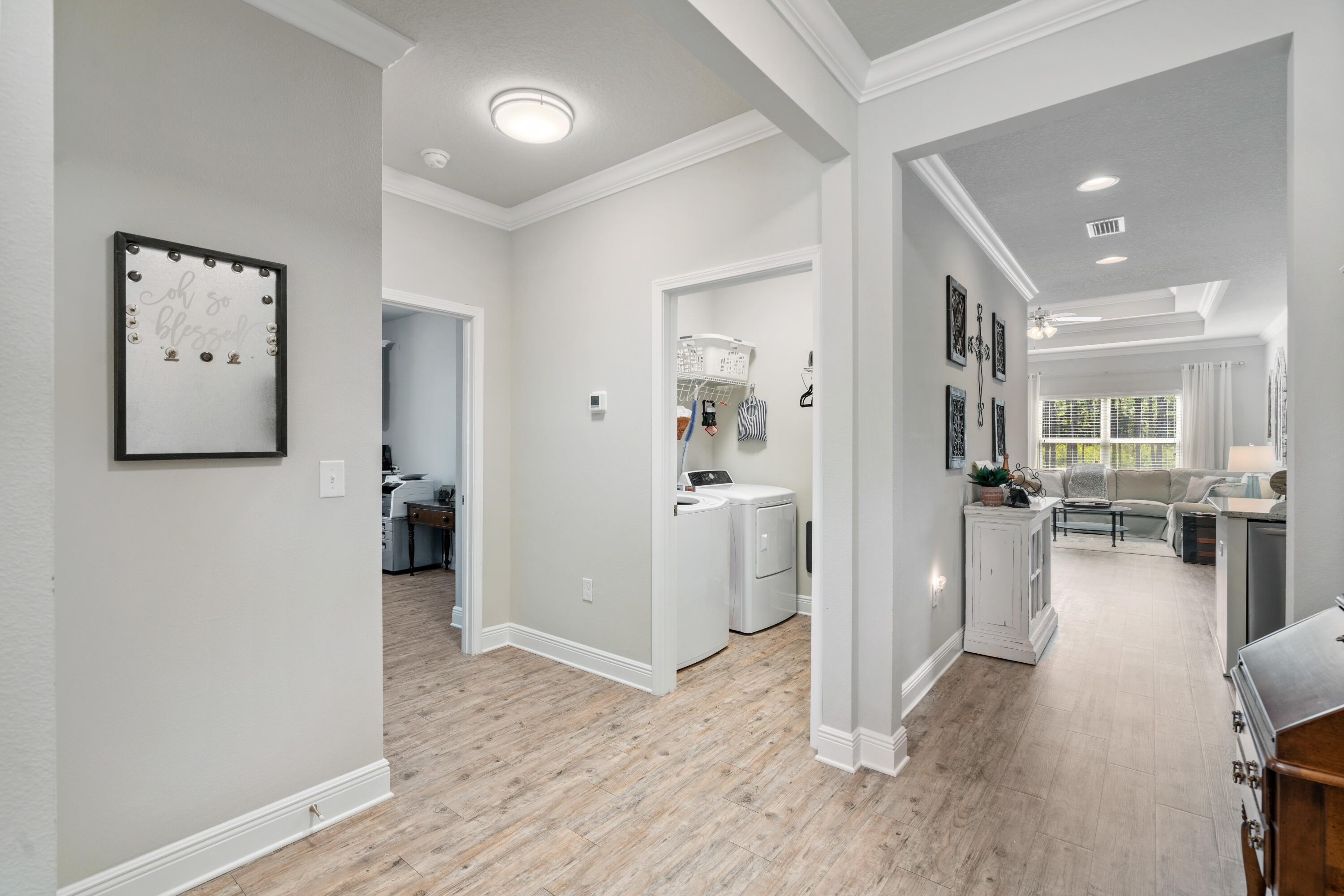 Hallway with wood-look floors, laundry area, and an opening to the furnished living room.