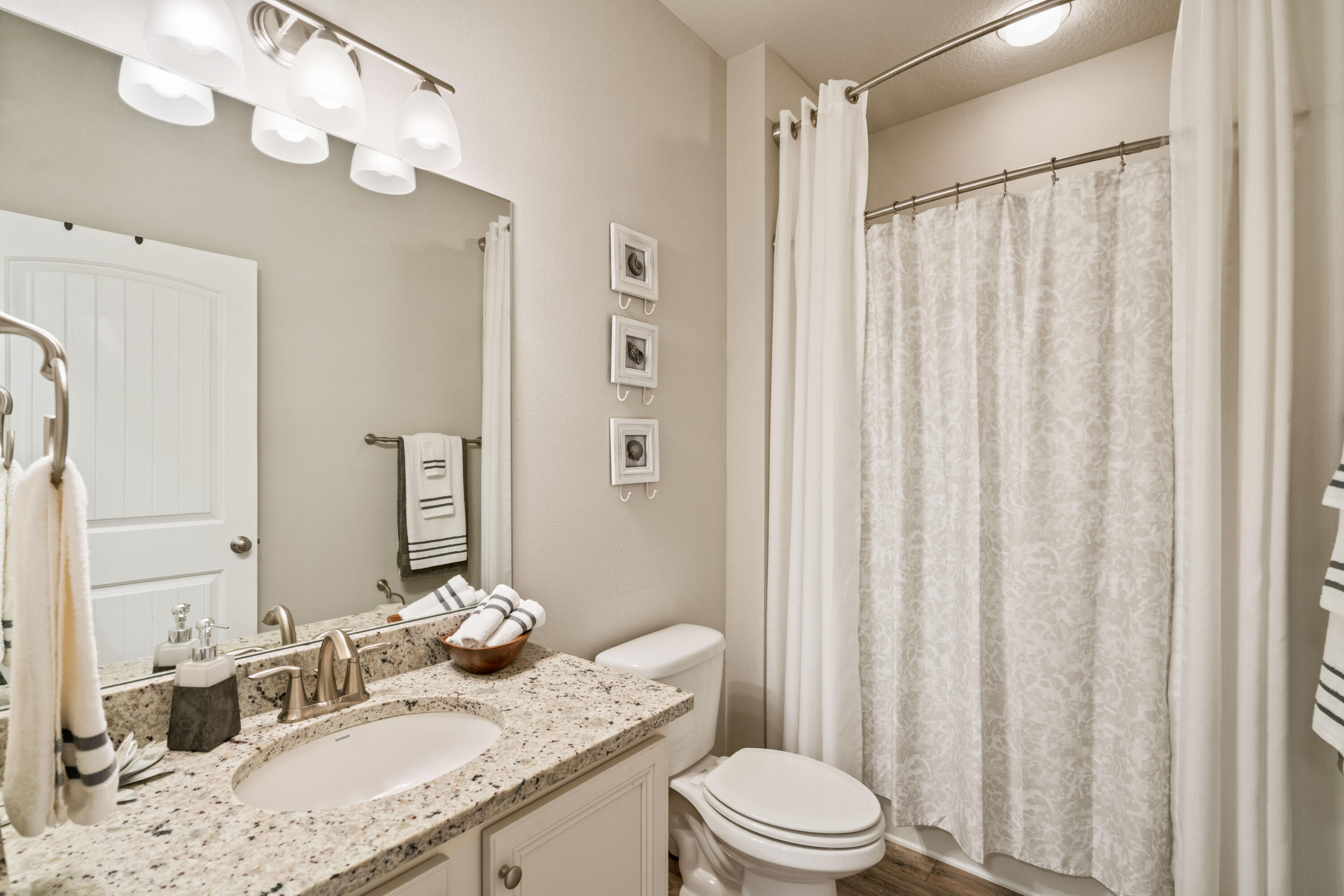 Bathroom with a granite vanity, oval sink, and patterned shower curtain.