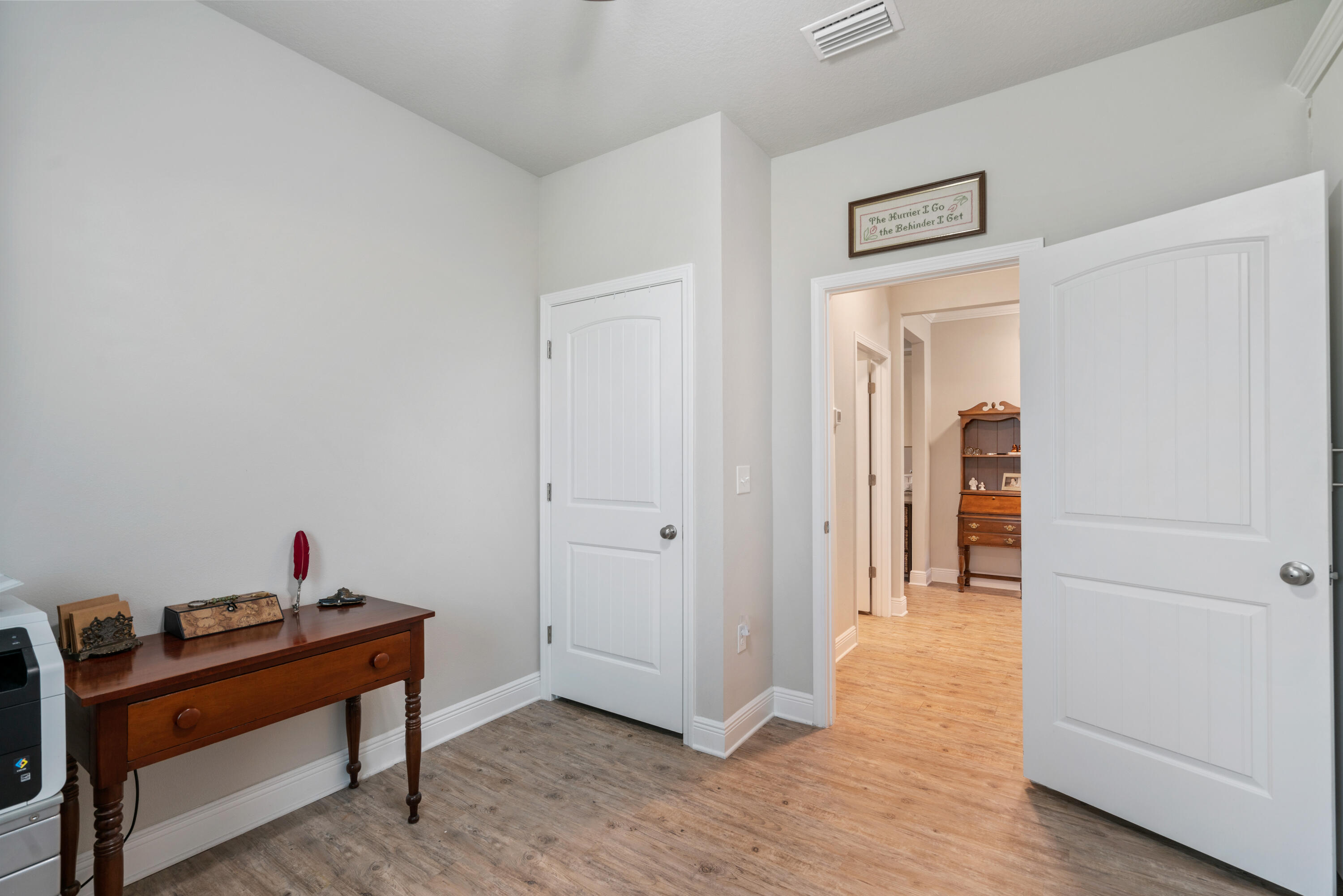 Furnished interior with gray wood-look flooring and an open doorway to a warm-lit hall.
