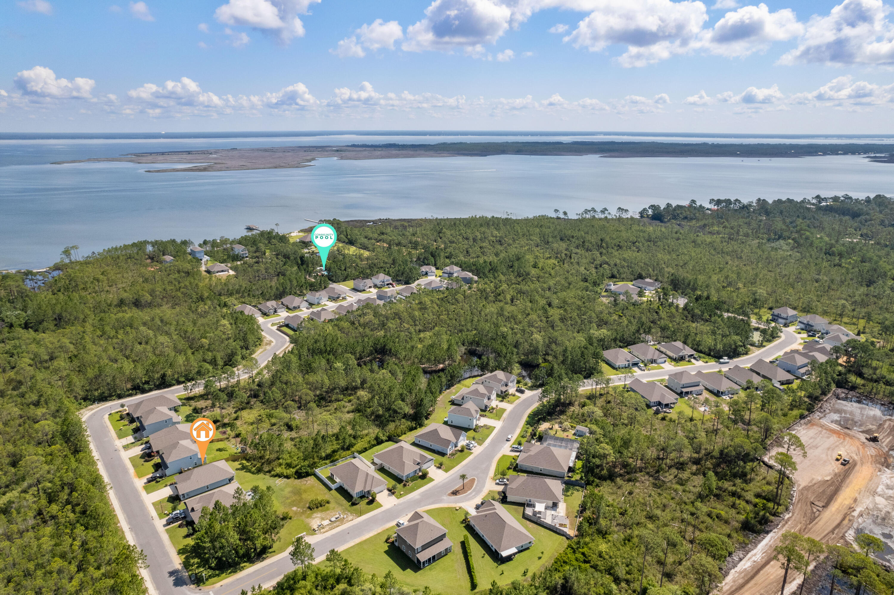 Aerial neighborhood beside a bay, with the featured home and community pool marked among tree-lined streets.