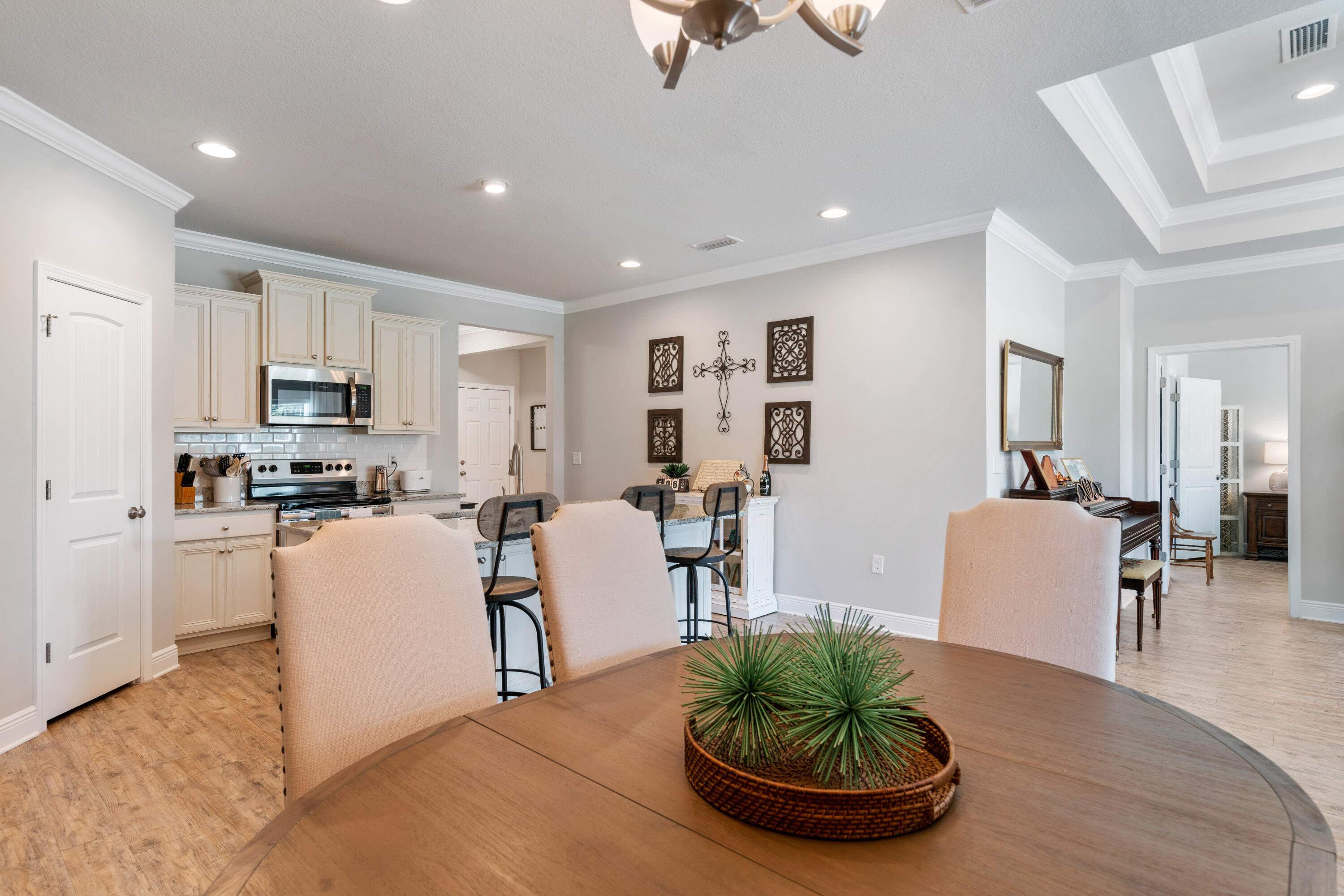 Open kitchen and dining area with cream cabinets, stainless appliances, and a round wood table.