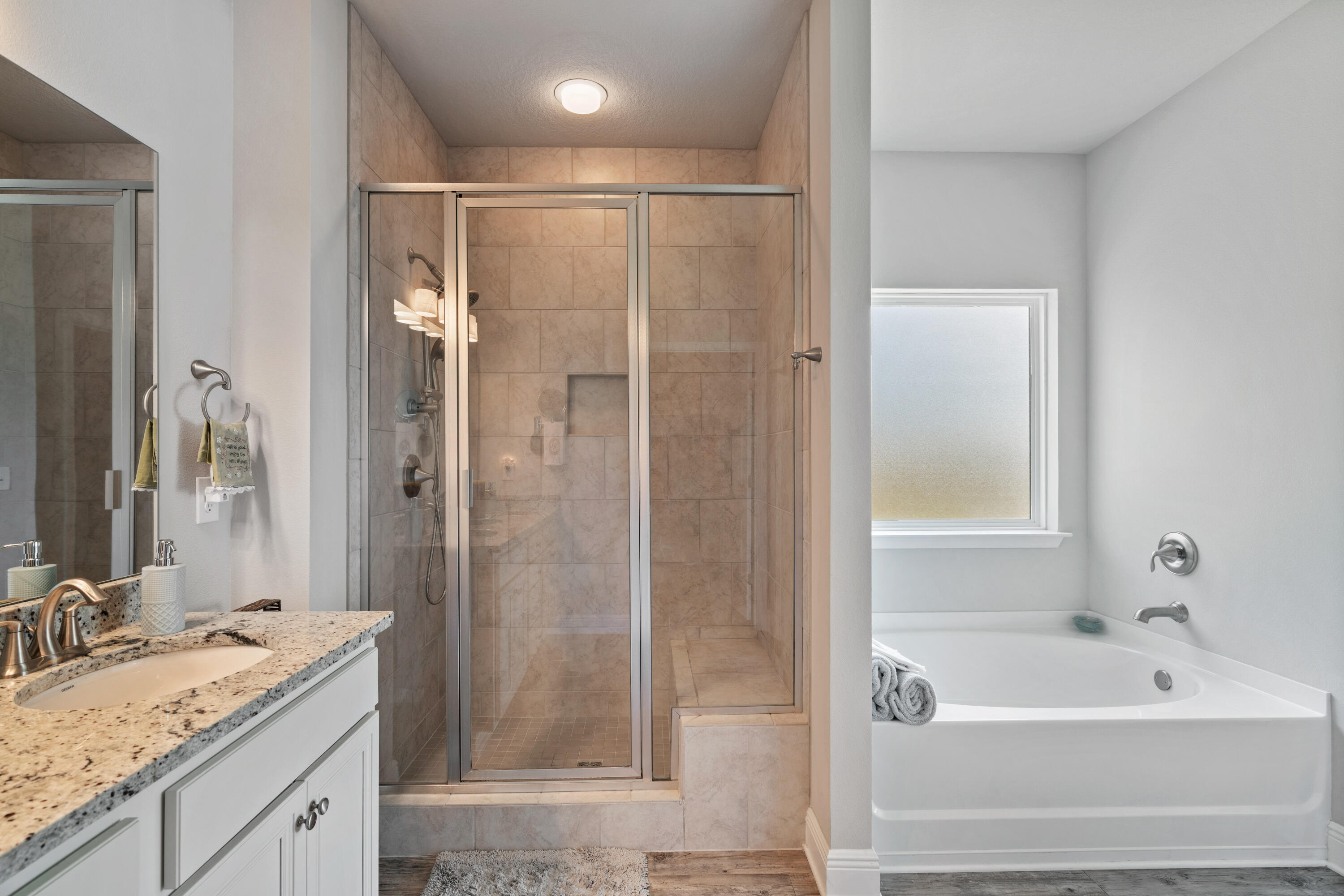 Bathroom with a glass-enclosed tile shower, soaking tub, and granite-topped vanity.