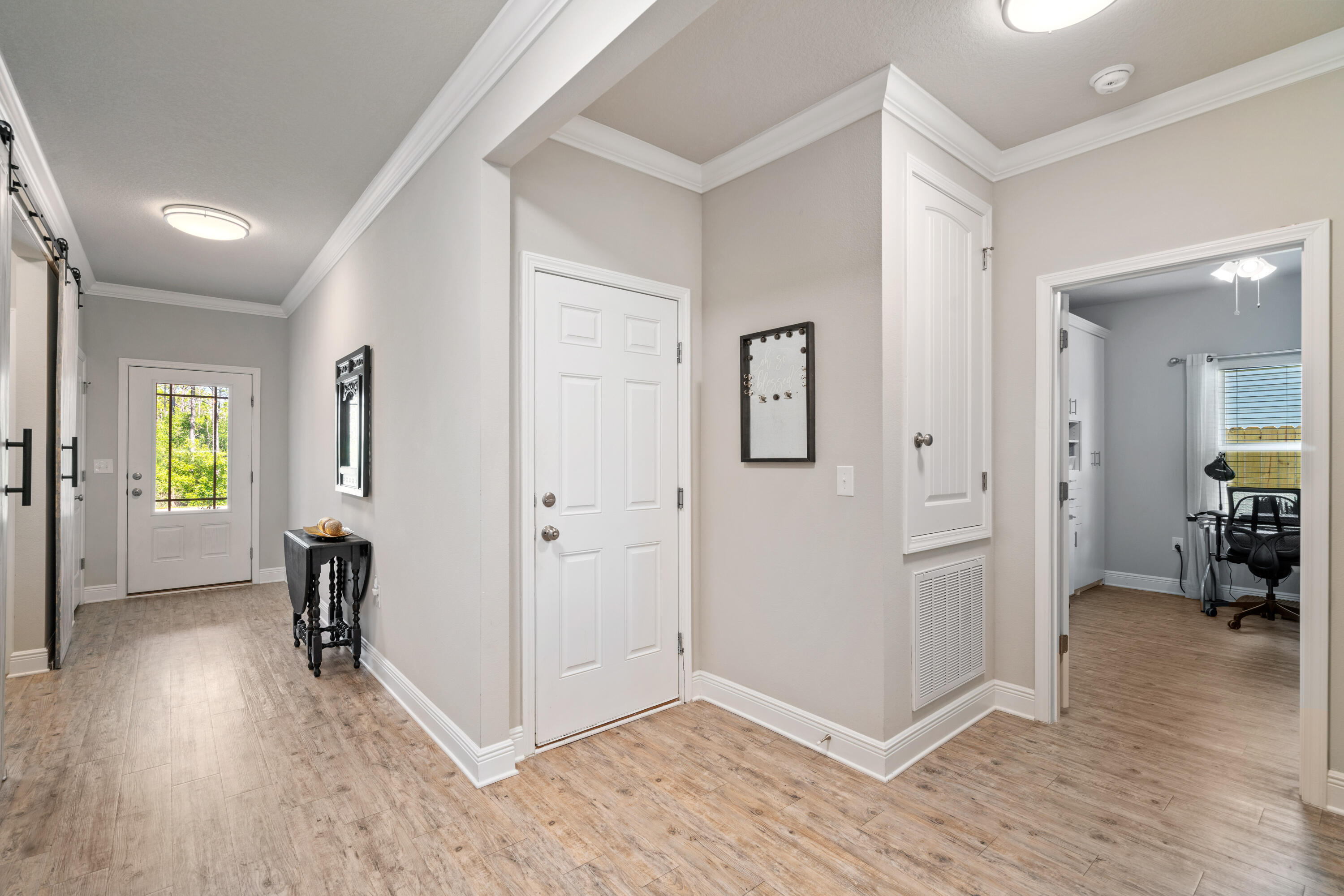 Entry hallway with wood-look flooring and paneled doors; an office is visible through the doorway.
