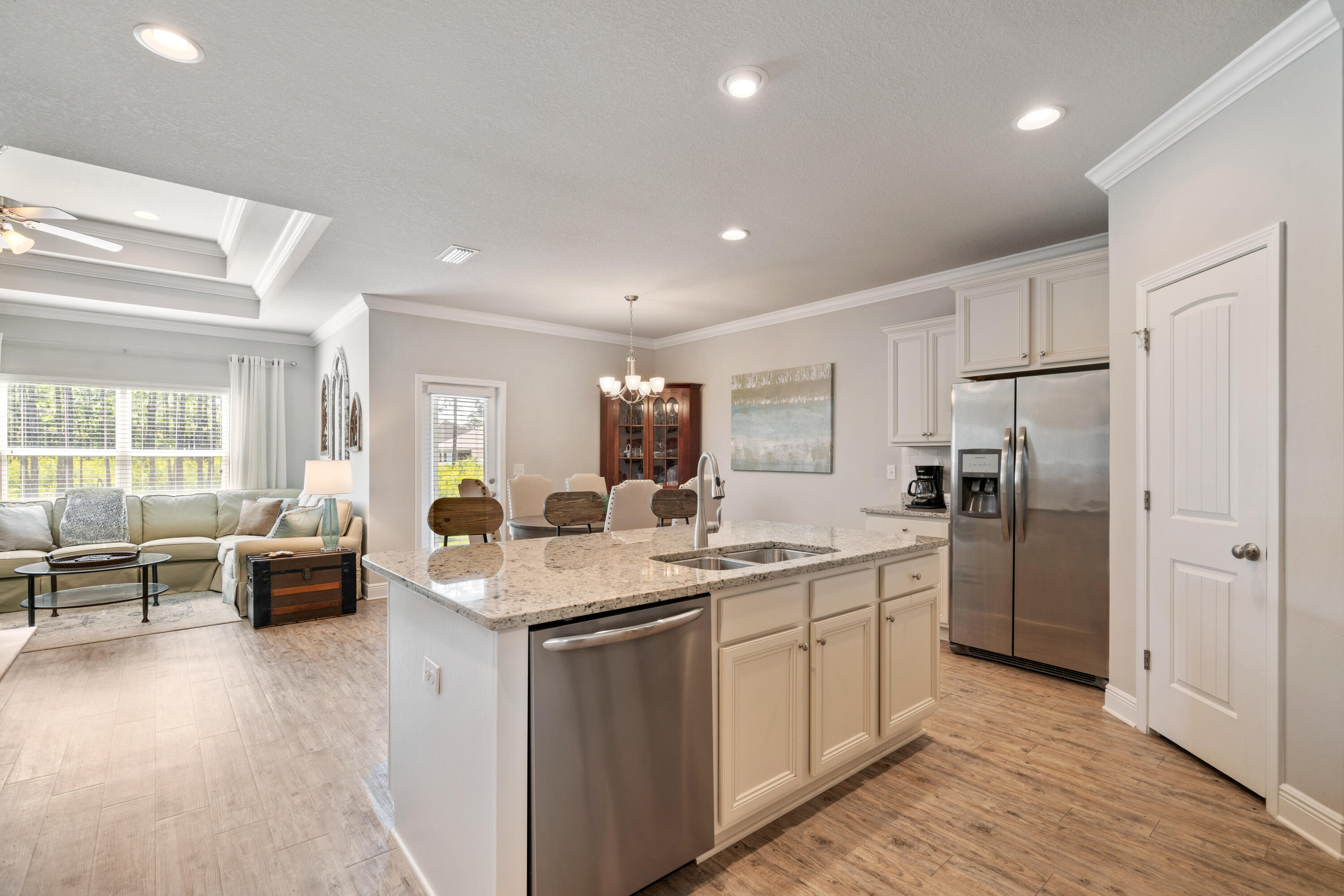 Open-plan kitchen with a granite island and stainless appliances beside a bright living room.