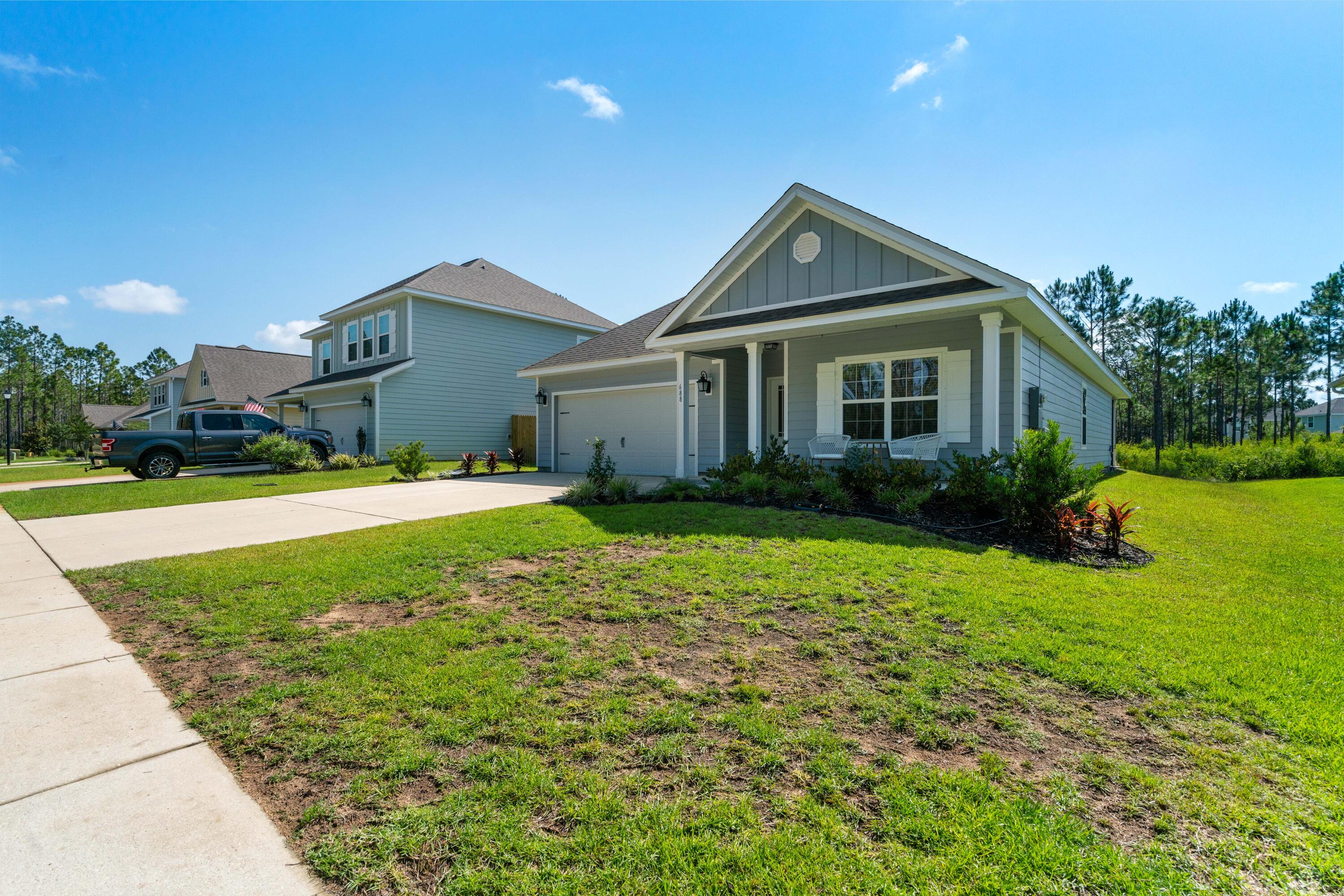 Gray-blue home with a gabled front porch, attached garage, and broad lawn.