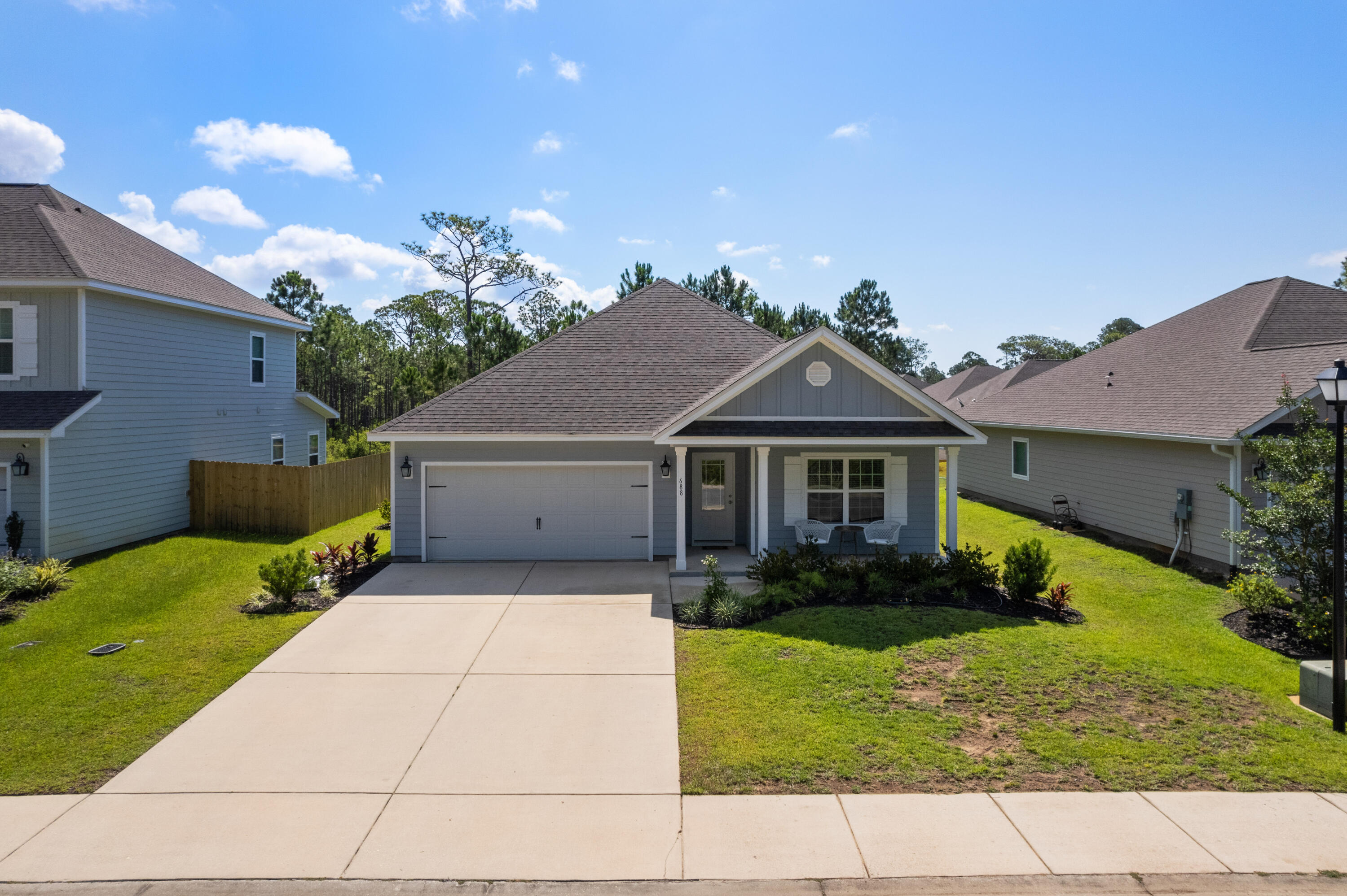 Gray single-story home with a two-car garage, covered porch, and broad concrete driveway.