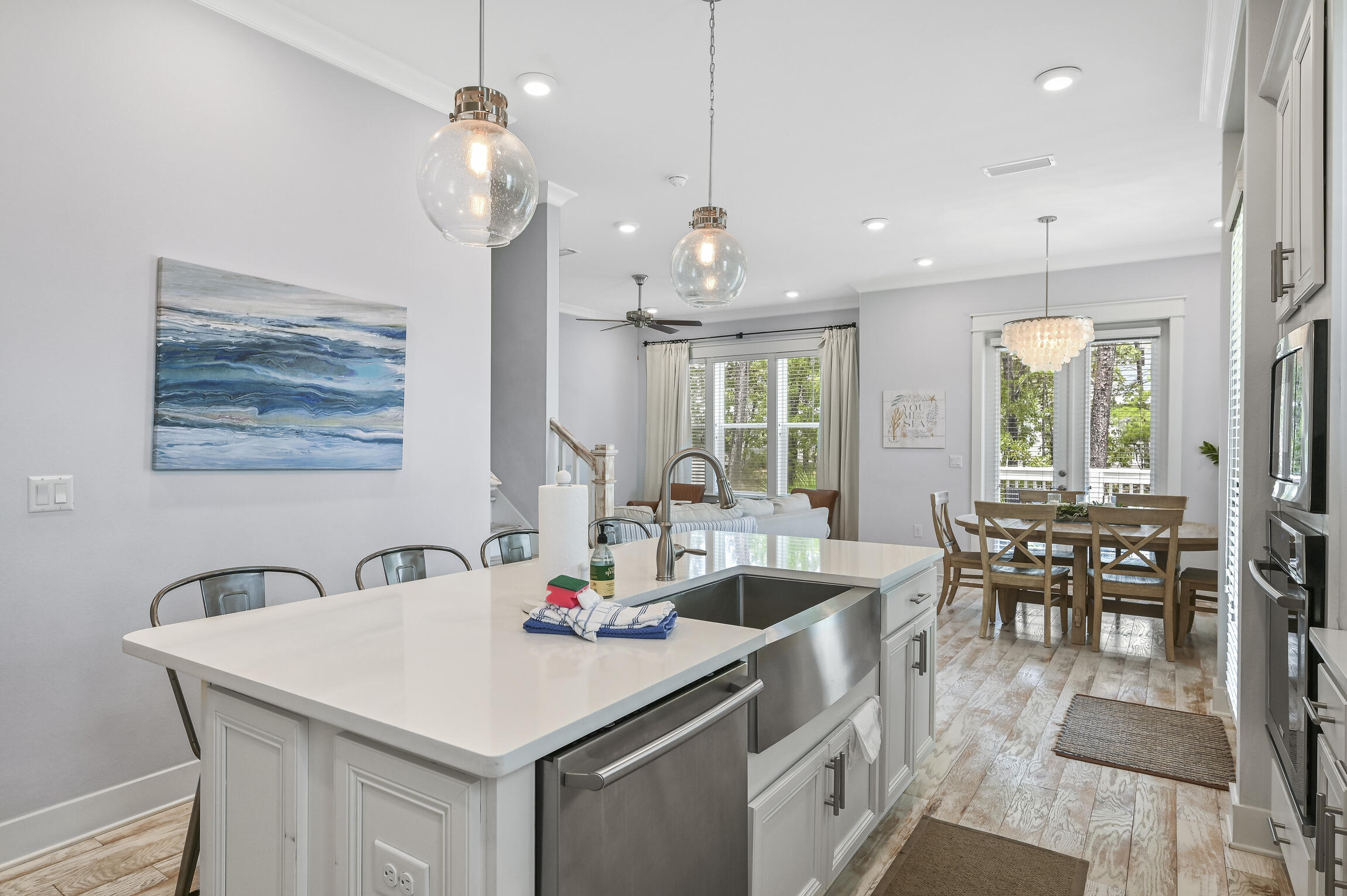 Bright kitchen with a large white island, stainless steel sink, and adjoining dining area.