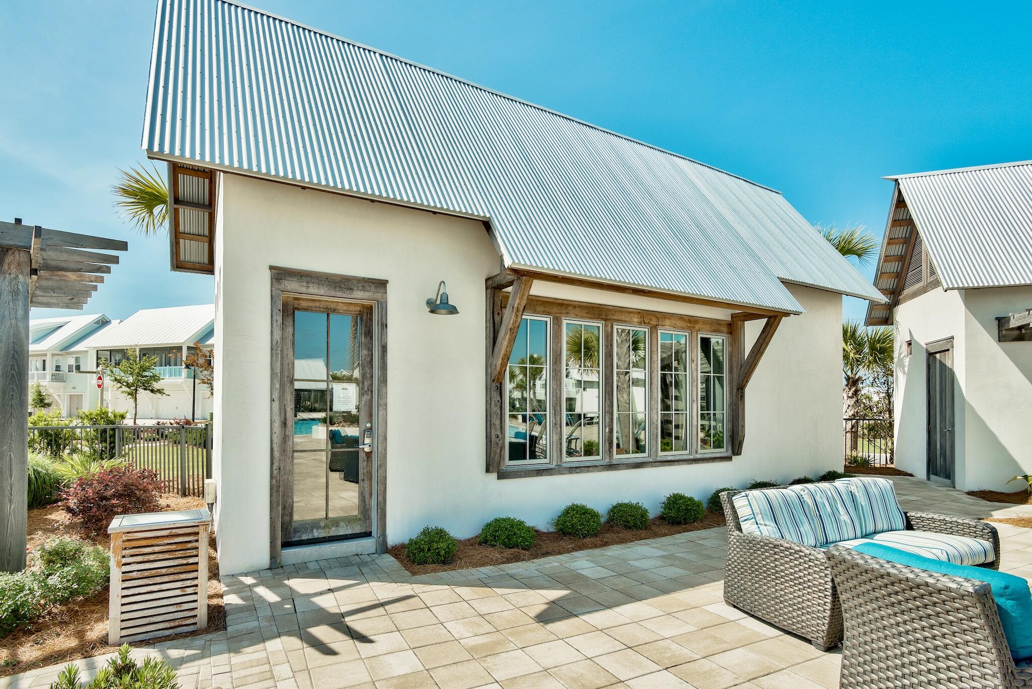 Home exterior with a steep metal roof and a paved patio with woven lounge seating.