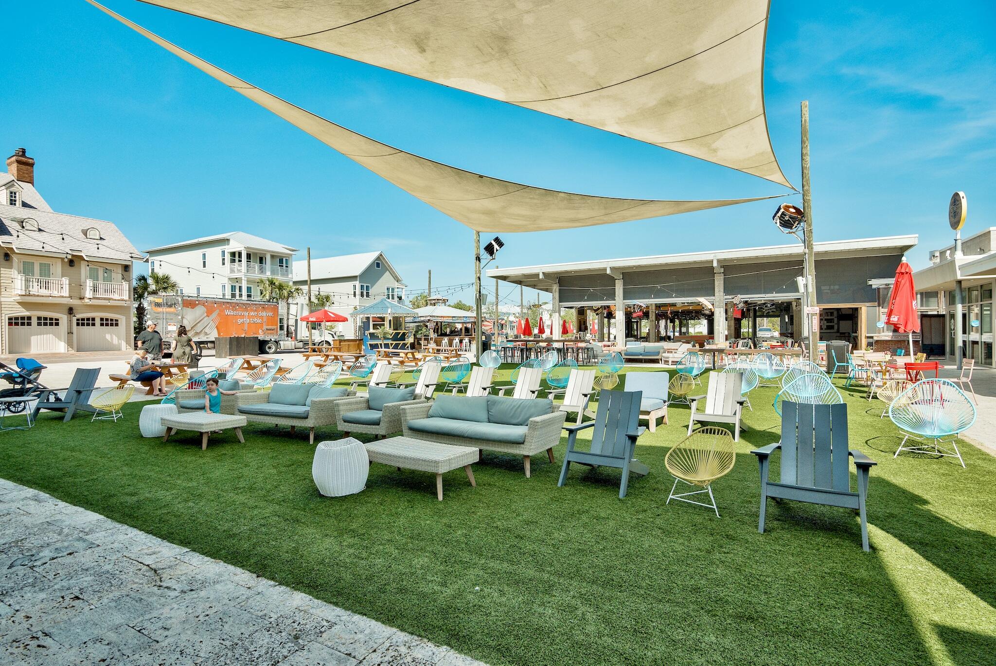 Outdoor courtyard with lawn seating and large shade sails.