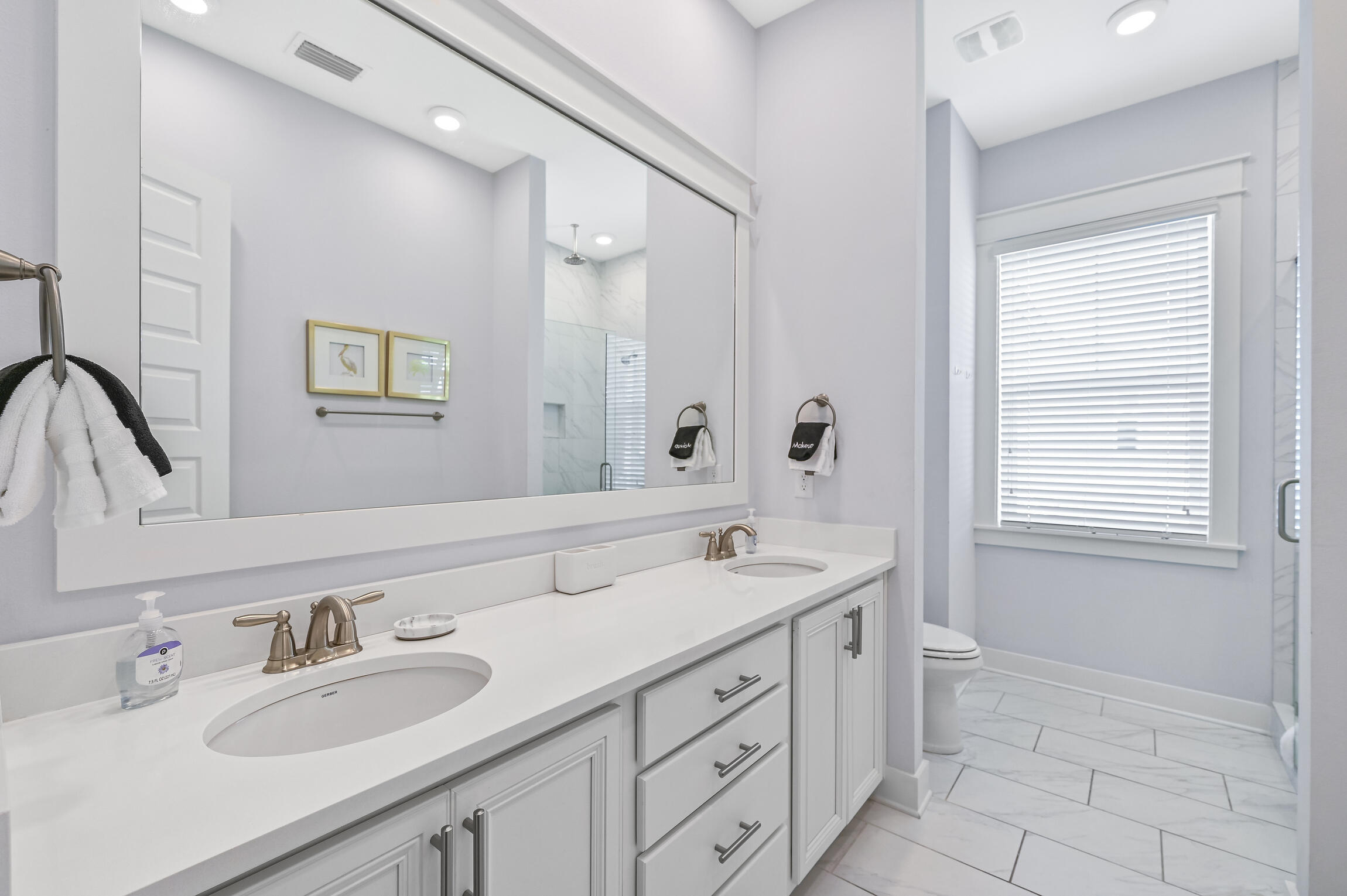 Bathroom with a long double-sink vanity and a window beside the shower.