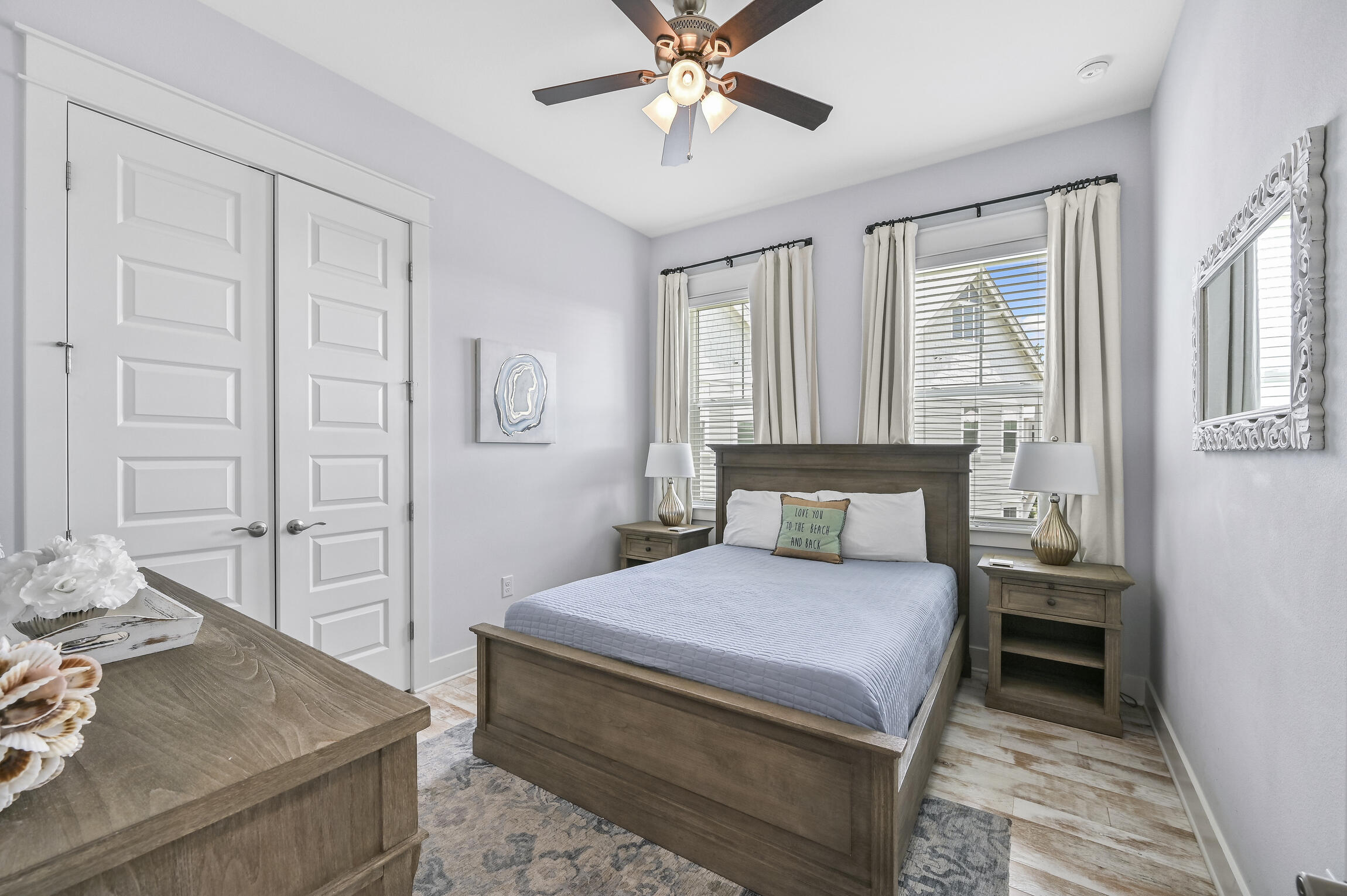 Bedroom with a dark wood bed, matching nightstands, and two curtained windows.