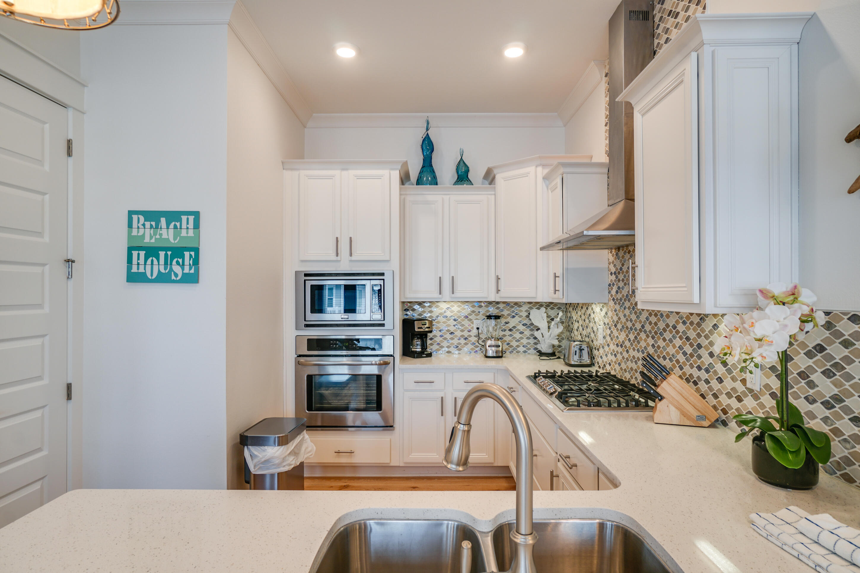 Kitchen with white cabinets, mosaic backsplash, stainless steel appliances, and a double-basin sink.